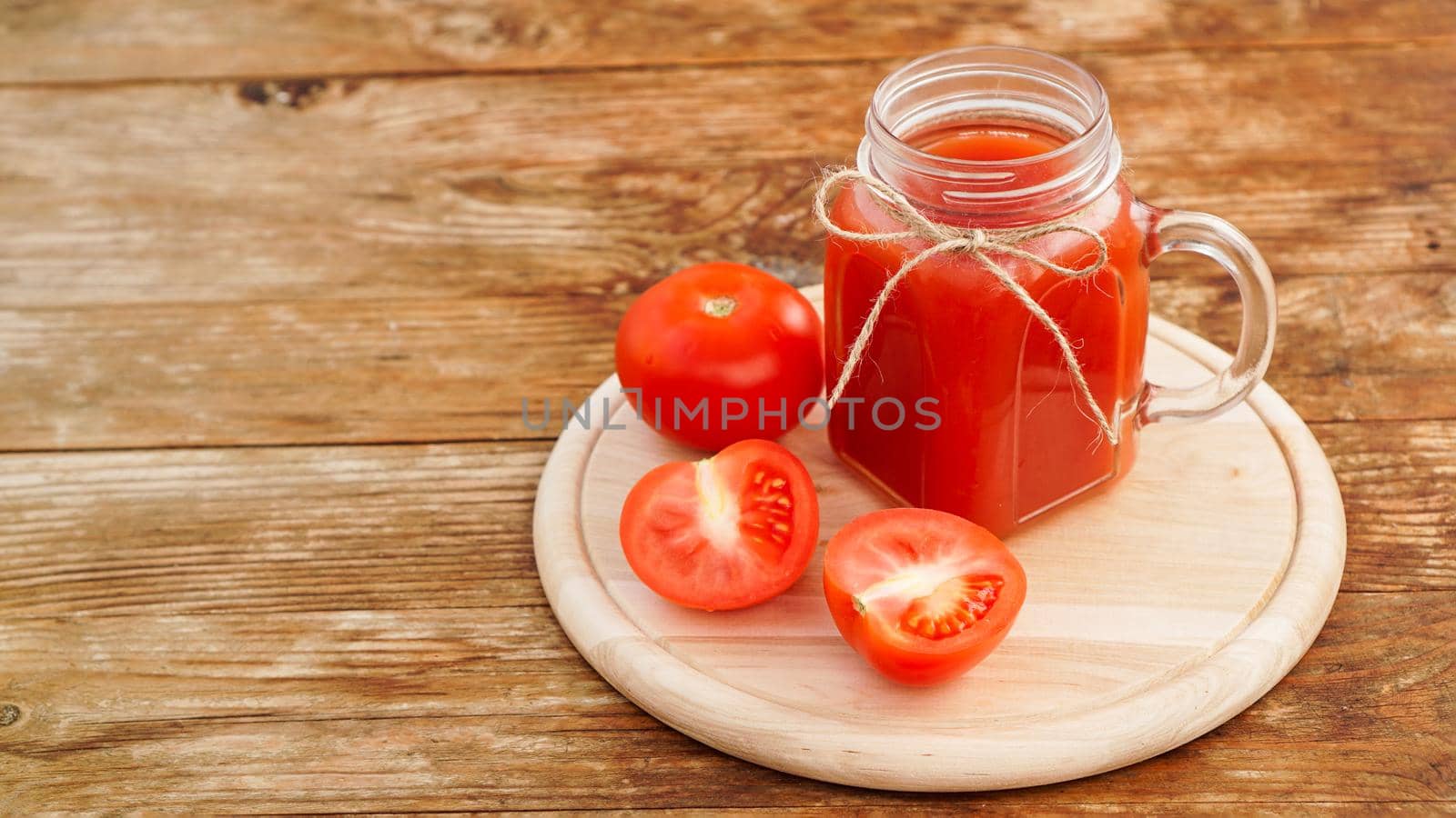 Glass of tomato juice on wooden table. Fresh tomato juice and chopped tomatoes on wooden board