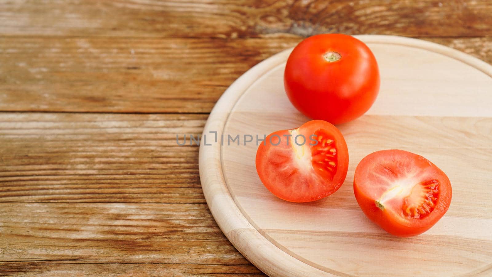 Whole and cut tomato on a wooden board for slicing. Rustic style and wood by natali_brill