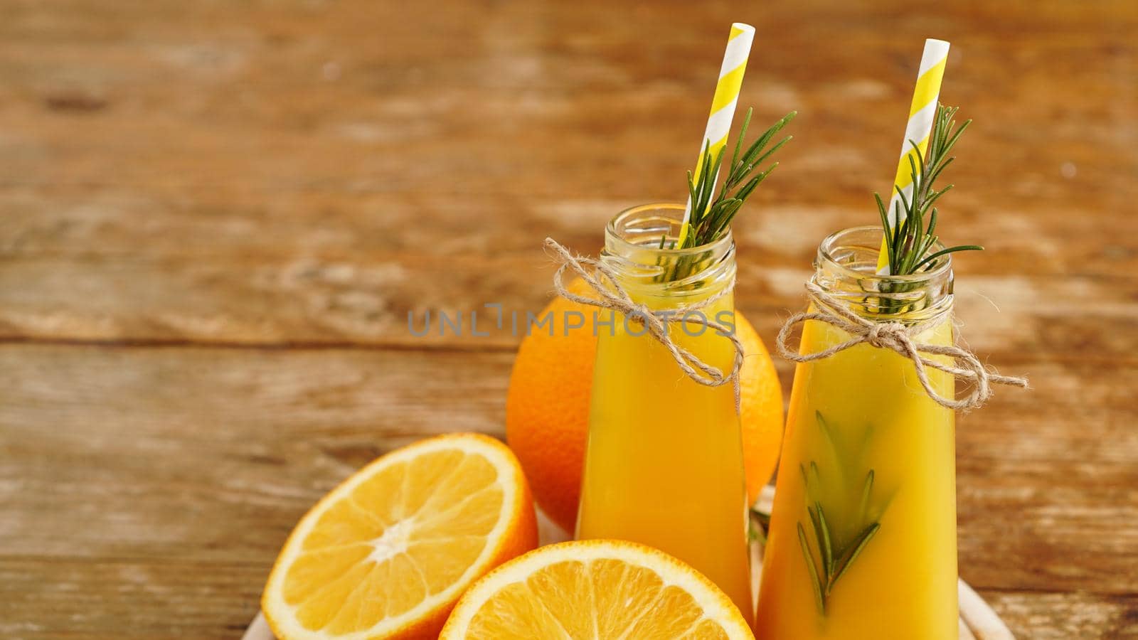 Orange juice in glass bottles. The juice is decorated with a sprig of rosemary by natali_brill