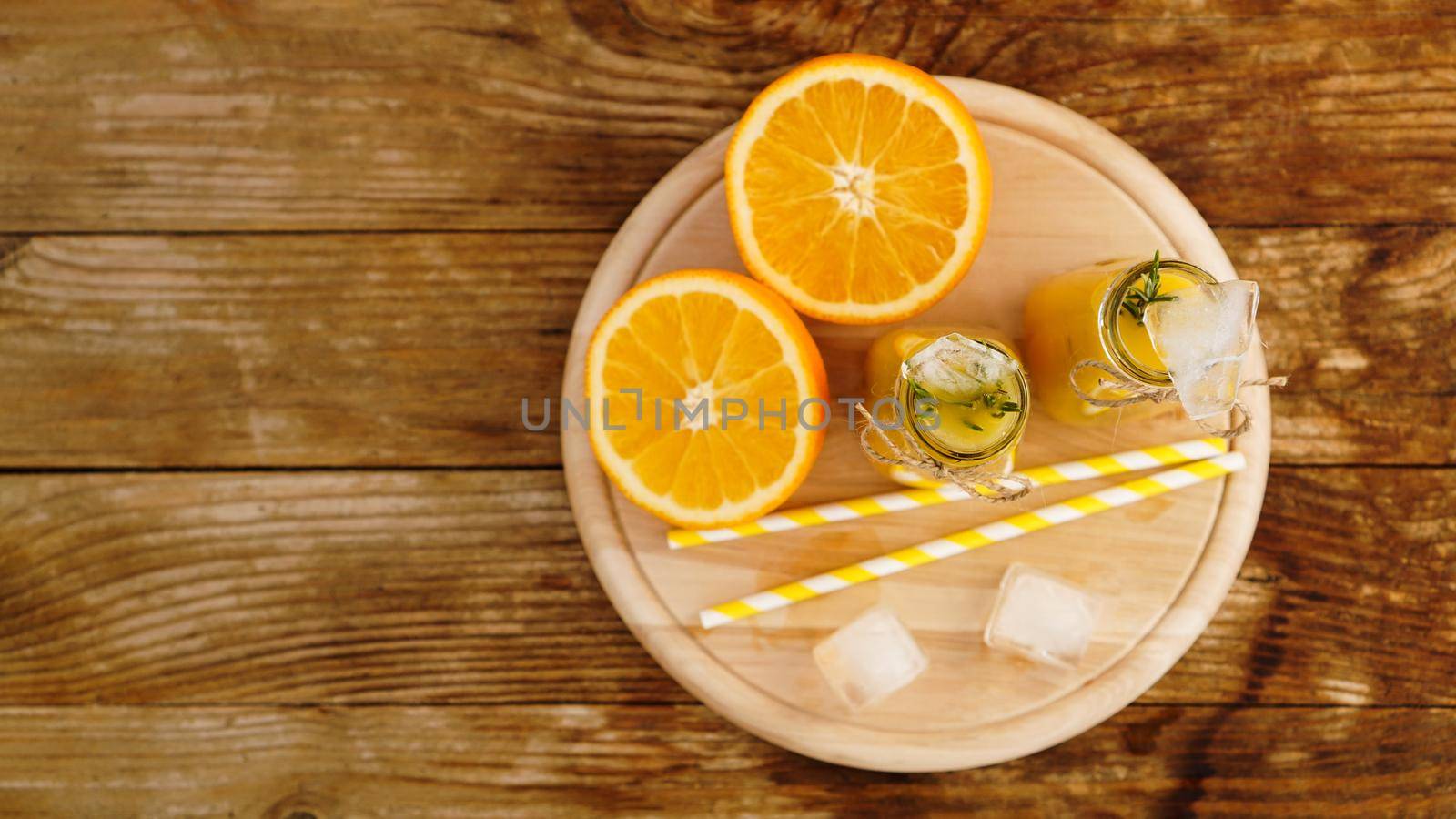 Orange juice on a wooden tray. Sliced orange and ice cubes. Snack at the resort, coolness on a hot summer day. Top view