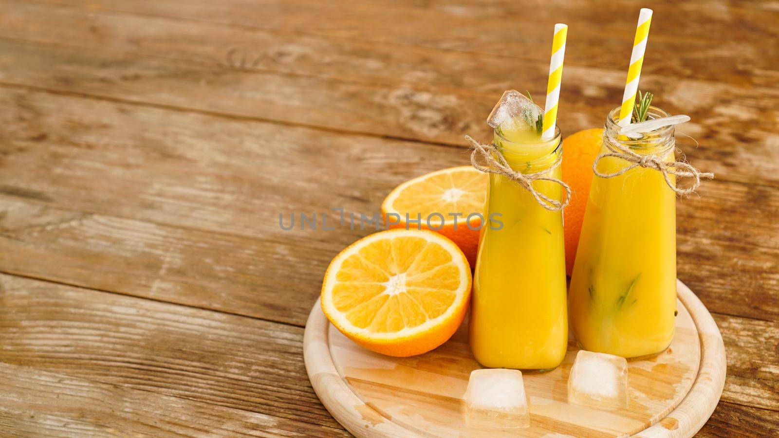 Orange juice on a wooden tray. Sliced orange and ice cubes. Snack at the resort, coolness on a hot summer day.