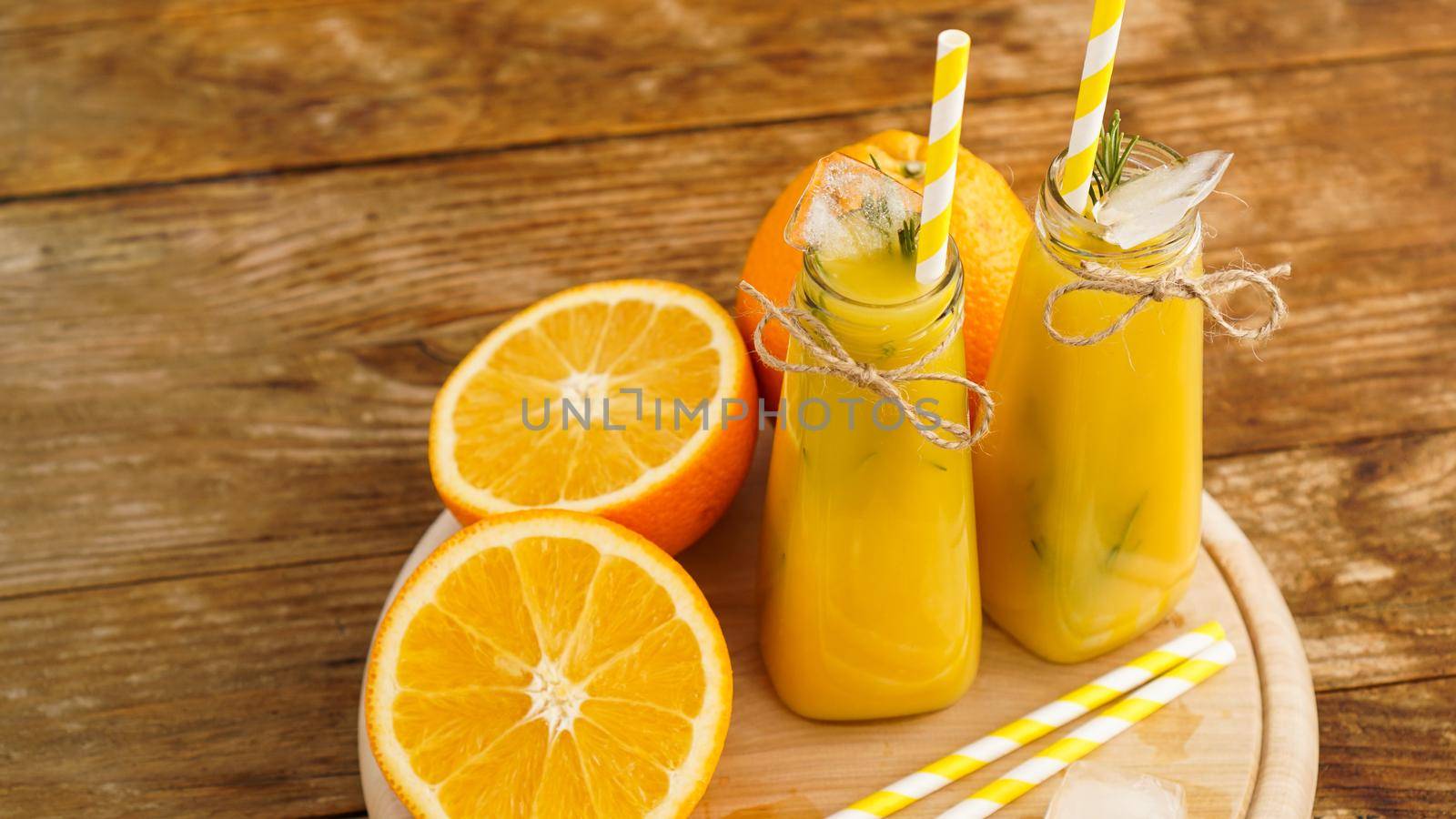 Orange juice on a wooden tray. Sliced orange and ice cubes. Snack at the resort, coolness on a hot summer day.