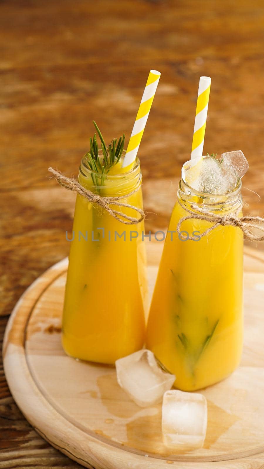 Bottle of orange juice with ice cubes, selective focus. Wooden background. Vertical photo