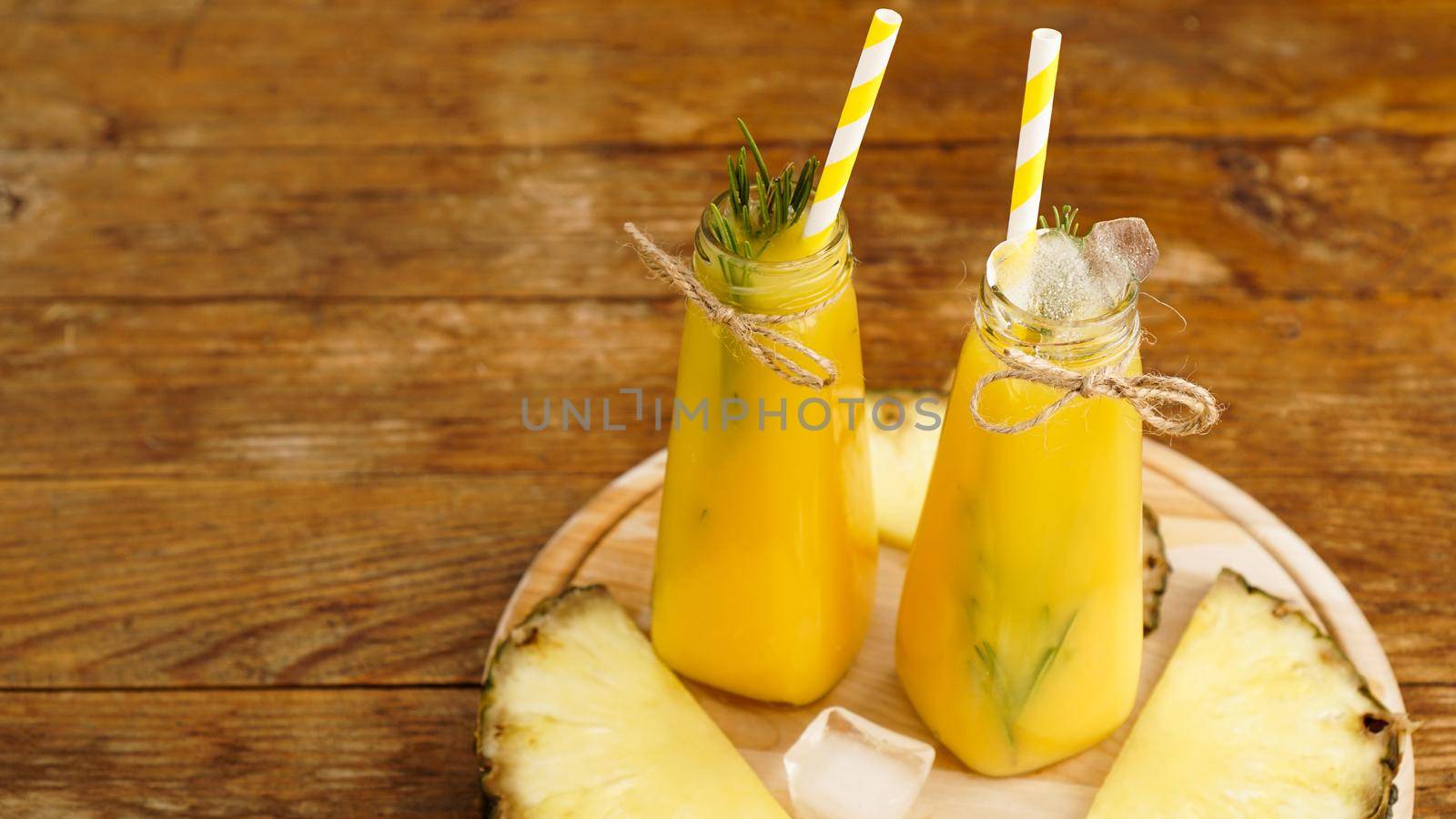 Fresh made Pineapple Juice with Ice in a small glass bottle on wooden background by natali_brill