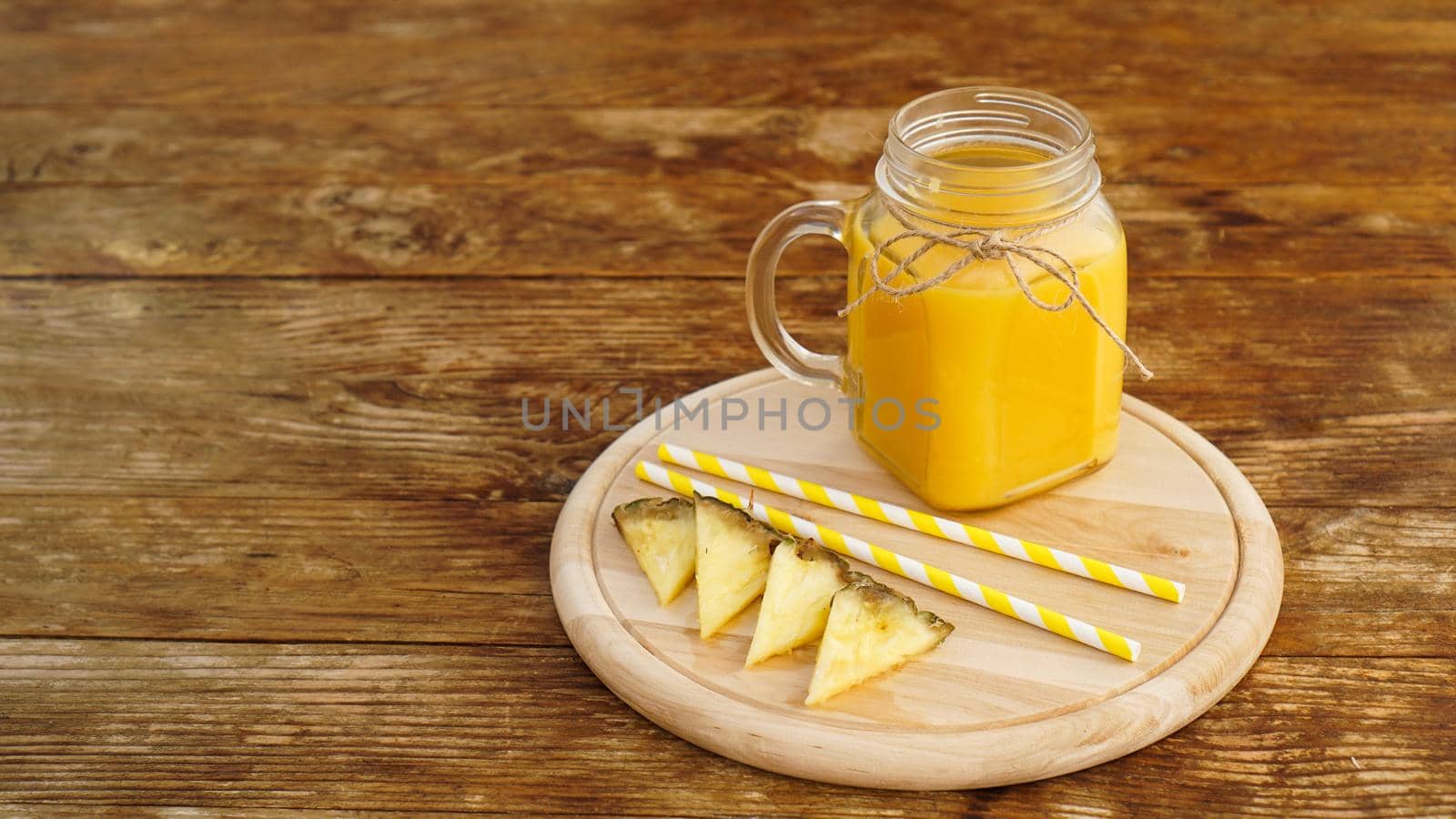 Bottles of pineapple juice on a wooden table. Yellow drink and fresh pineapple. Snack at the resort on a wooden tray. Summer photo