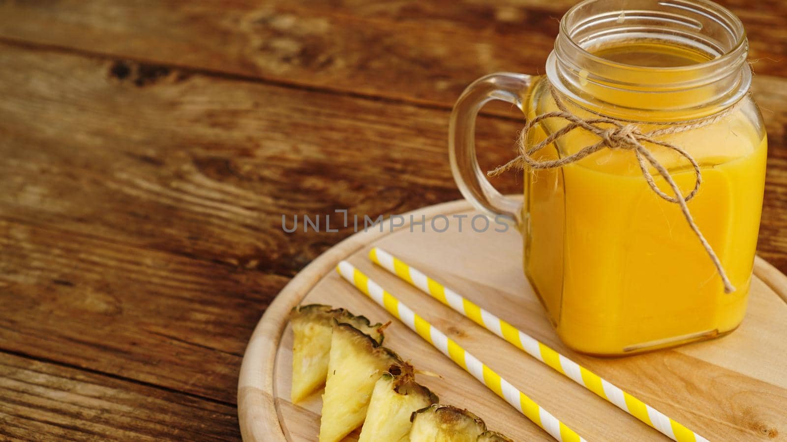 Bottles of pineapple juice on a wooden table. Yellow drink and fresh pineapple. Snack at the resort on a wooden tray. Summer photo