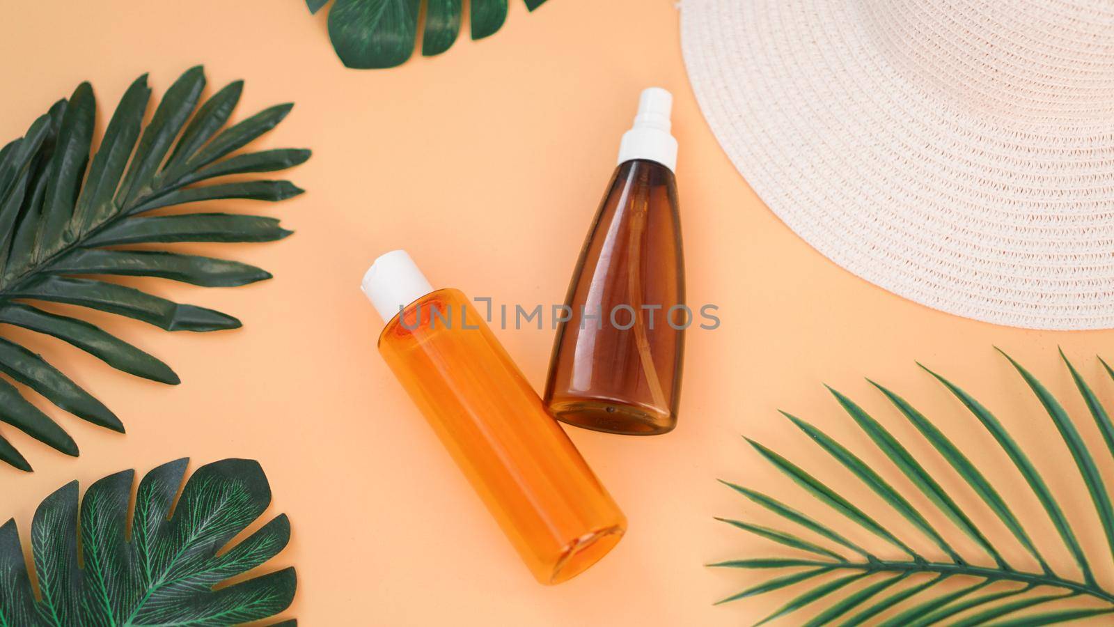 Sun cream, sun hat, lotion bottle on soft orange background. Sun protection. Summer time and holiday