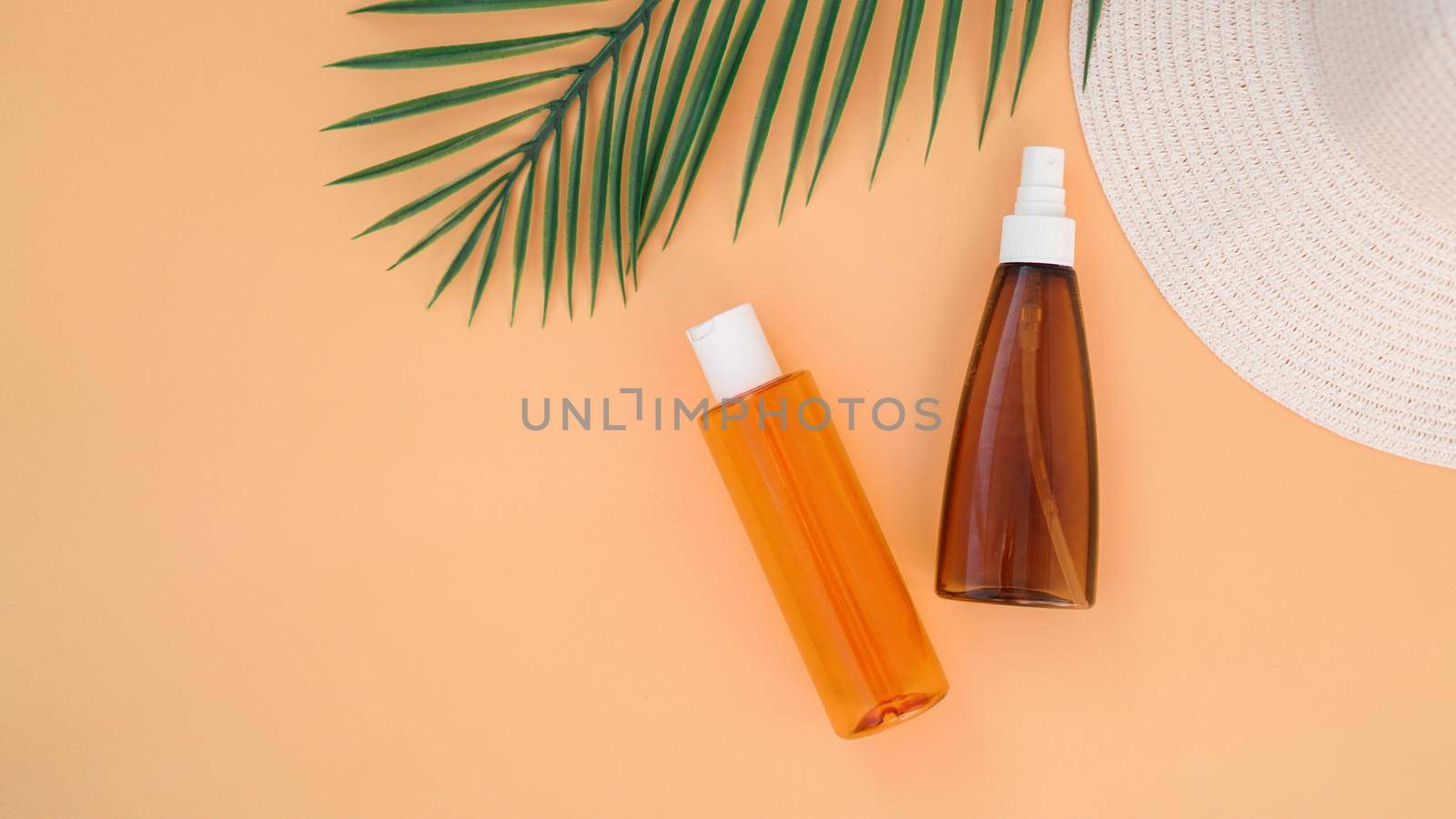 Sun cream, sun hat, lotion bottle on soft orange background. Sun protection. Summer time and holiday