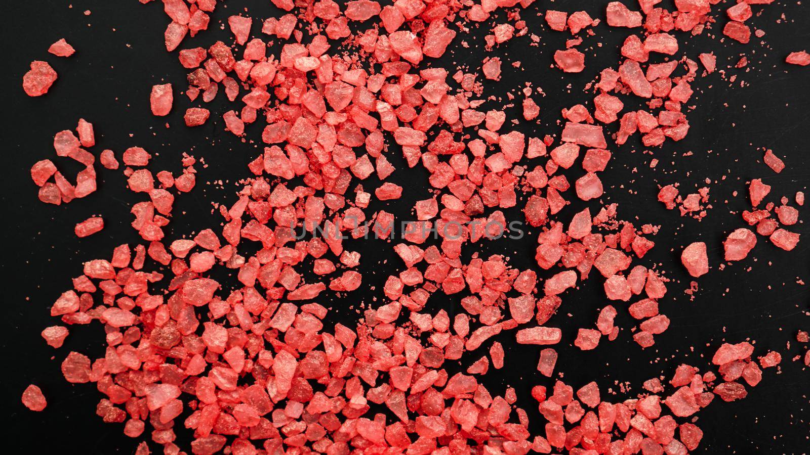 Salt isolated on a black background. A pile of red salt. Large crystalline salt. Beauty and health concept