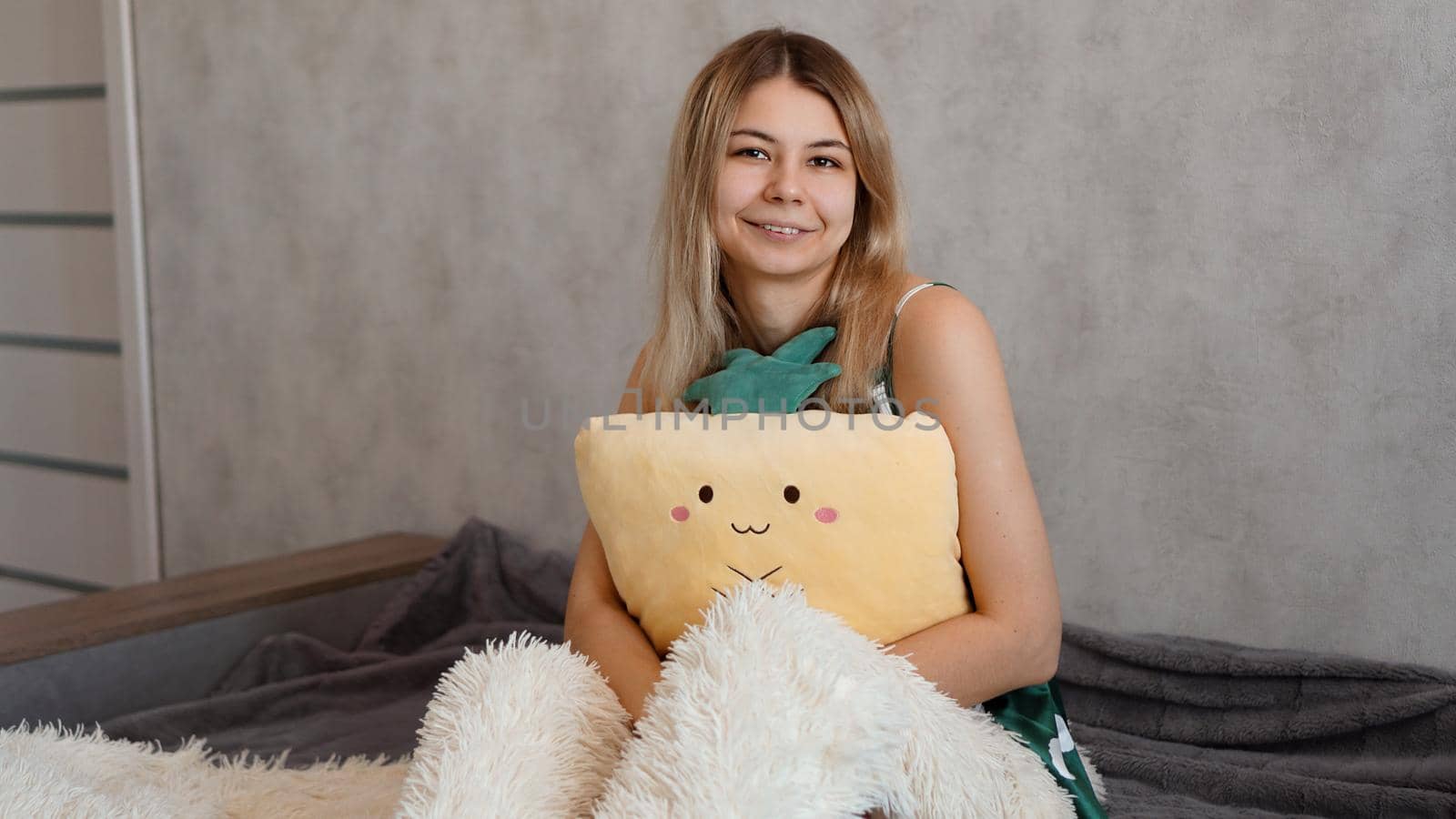 Happy blonde in the morning hugs a yellow pineapple pillow. Happy morning concept