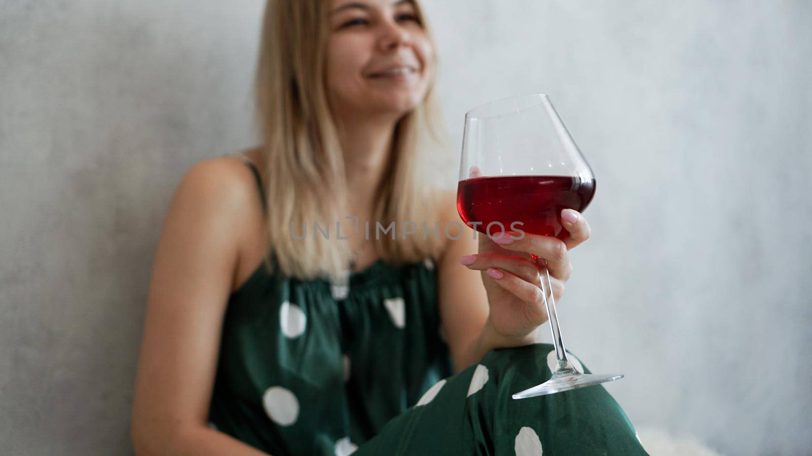 Girl in green pajamas in bed with a glass of red wine. Morning wine in bed