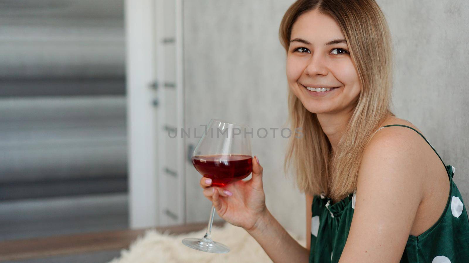 Girl in green pajamas in bed with a glass of red wine. Morning wine in bed