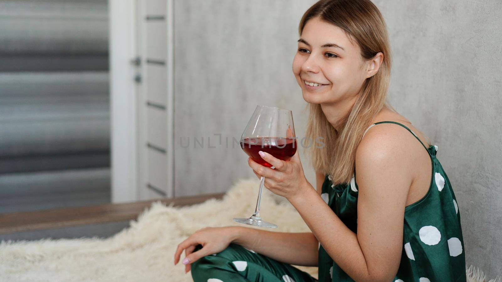 Girl in green pajamas in bed with a glass of red wine. Morning wine in bed