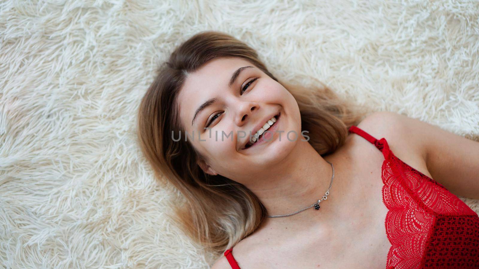 Beautiful young woman lying on a white shaggy blanket. View from above.