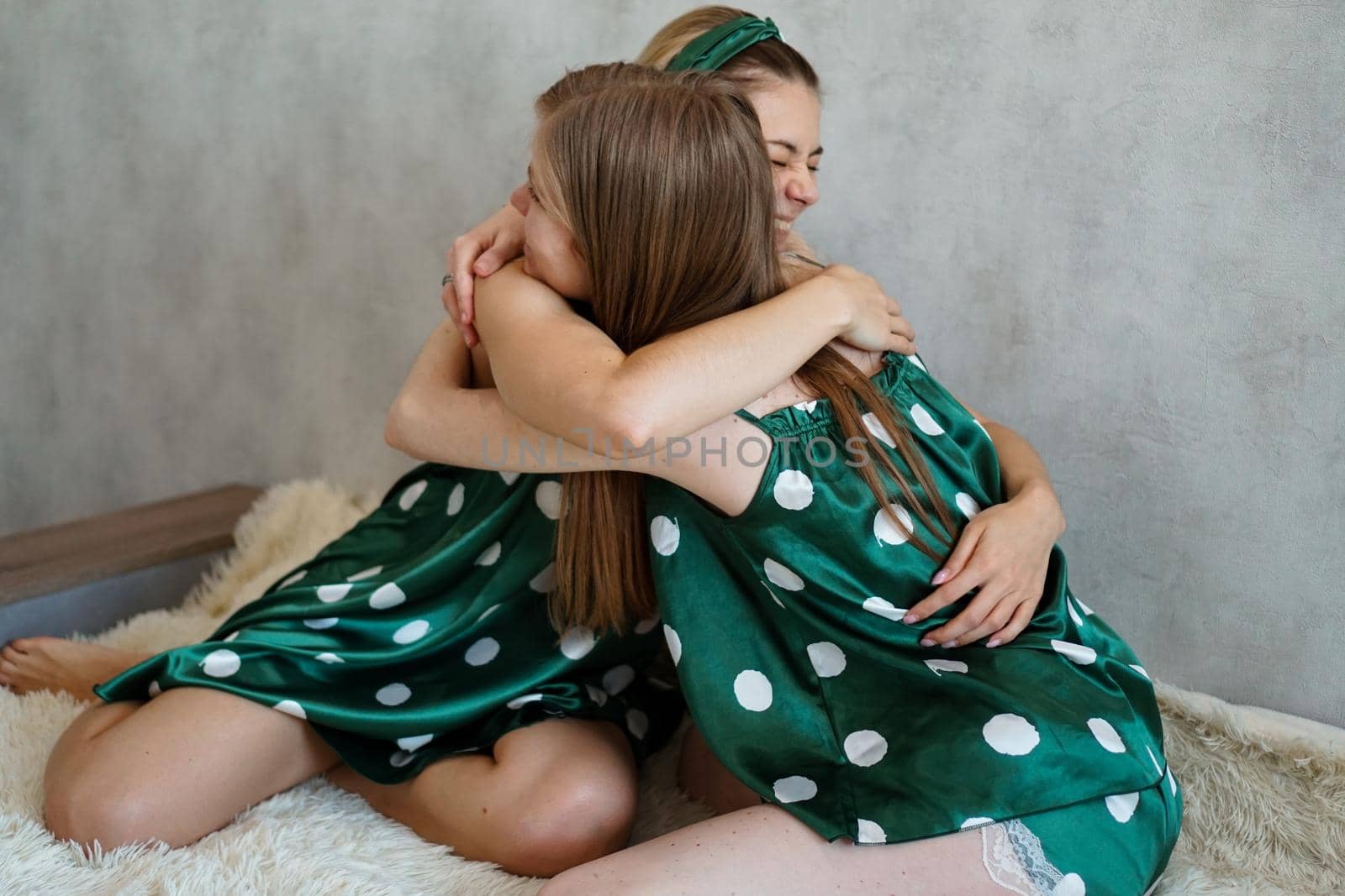 Lifestyle, friendship concept - two beautiful girls dressed in pajamas hugging by natali_brill