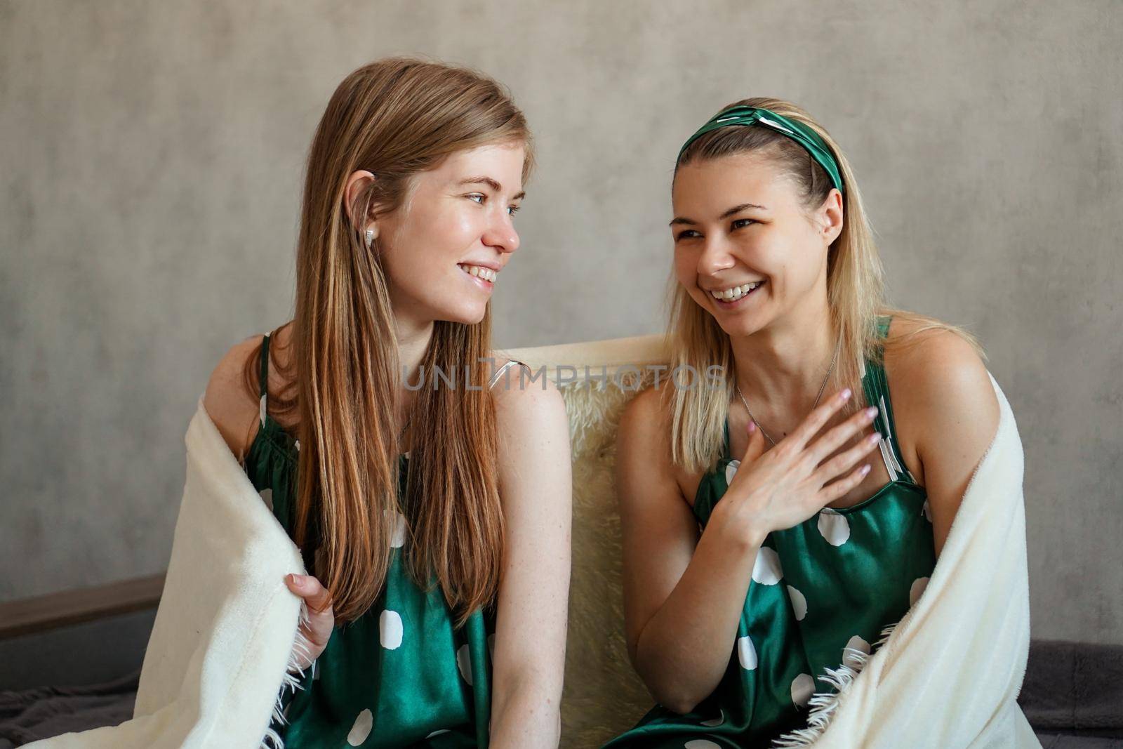 Two laughing young woman having fun when hiding under white blanket by natali_brill