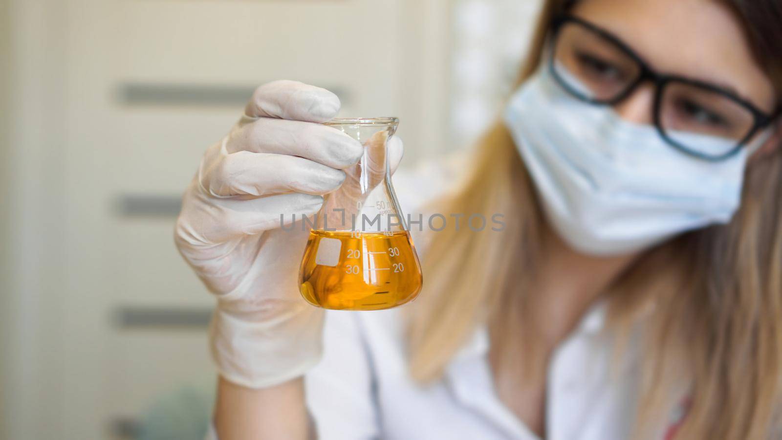 A woman holds a flask with a urine test. Diagnostics and analysis concept by natali_brill