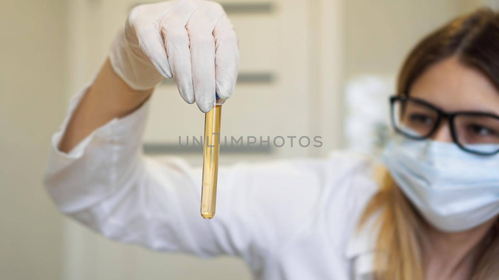 A woman holds a test tube with a urine test. Diagnostics and analysis concept by natali_brill