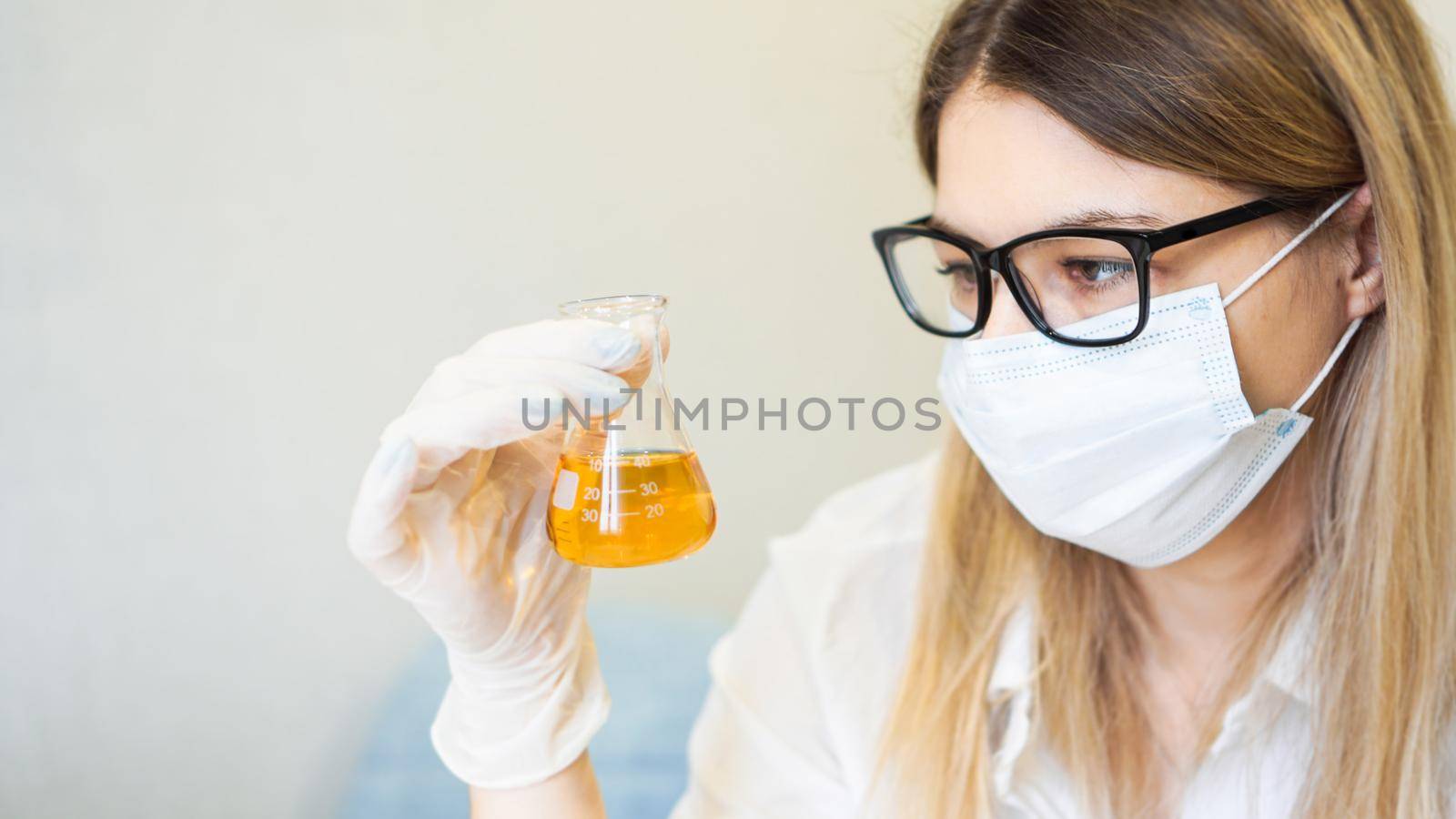 A woman holds a flask with a urine test. Diagnostics and analysis concept by natali_brill