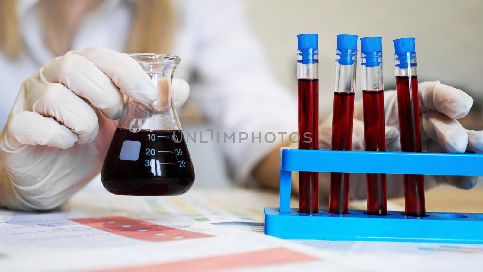 Hand of a scientific taking a blood sample tube from stand by natali_brill