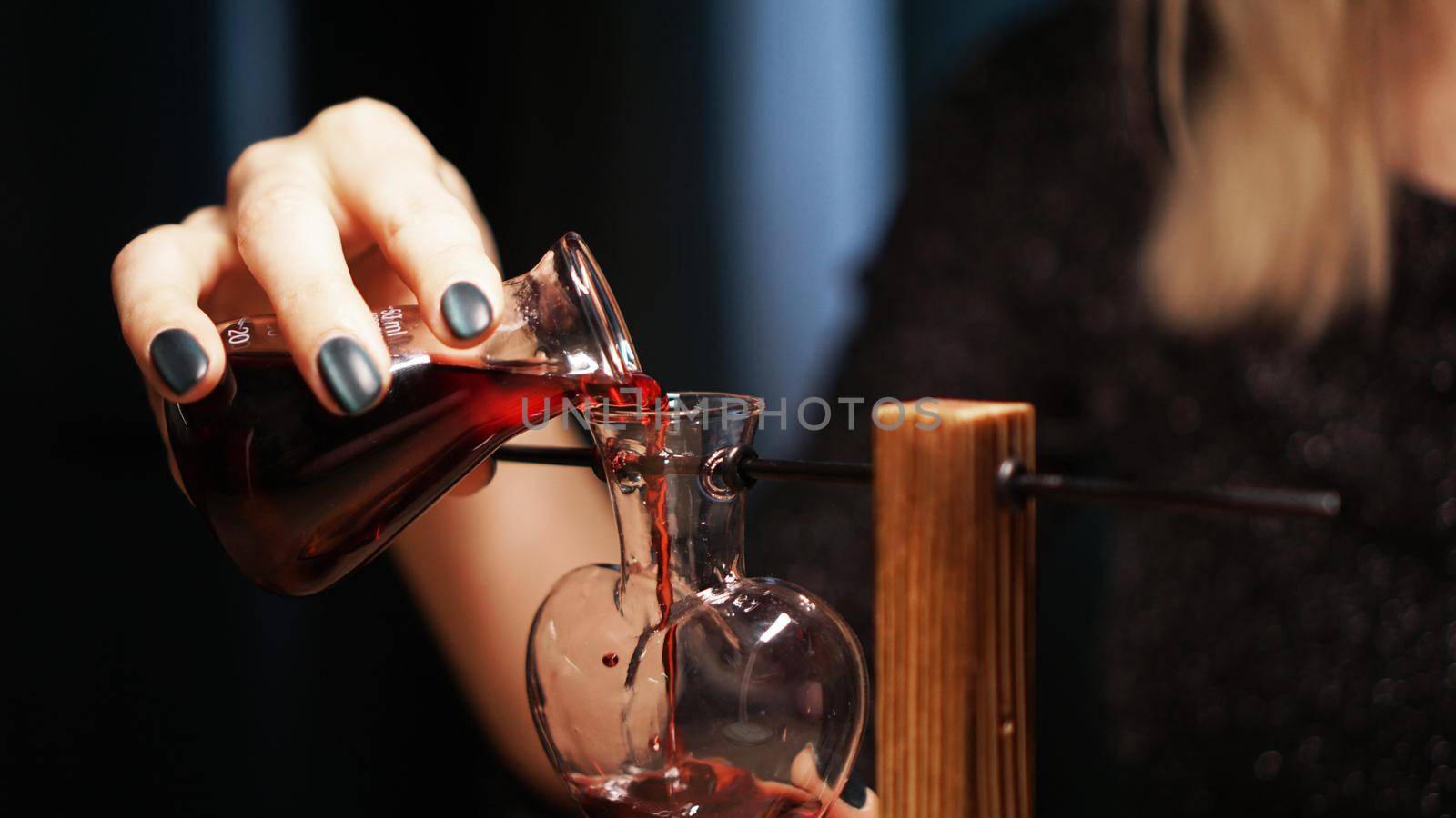 The woman witch prepares a potion. Red love potion in a heart-shaped glass jar by natali_brill