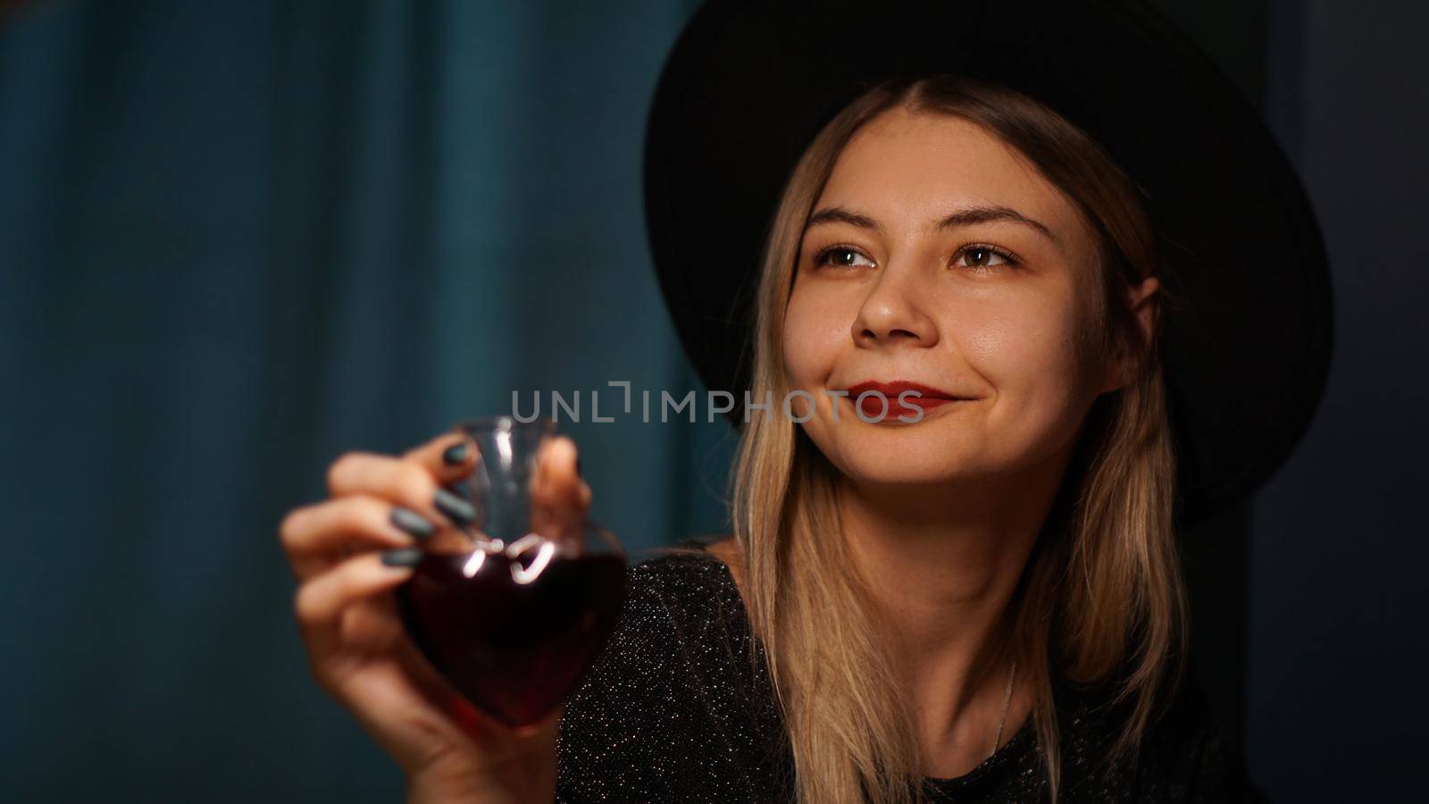 Cropped image of woman holding heart shaped glass jar of love potion. Beautiful young woman in a witch hat