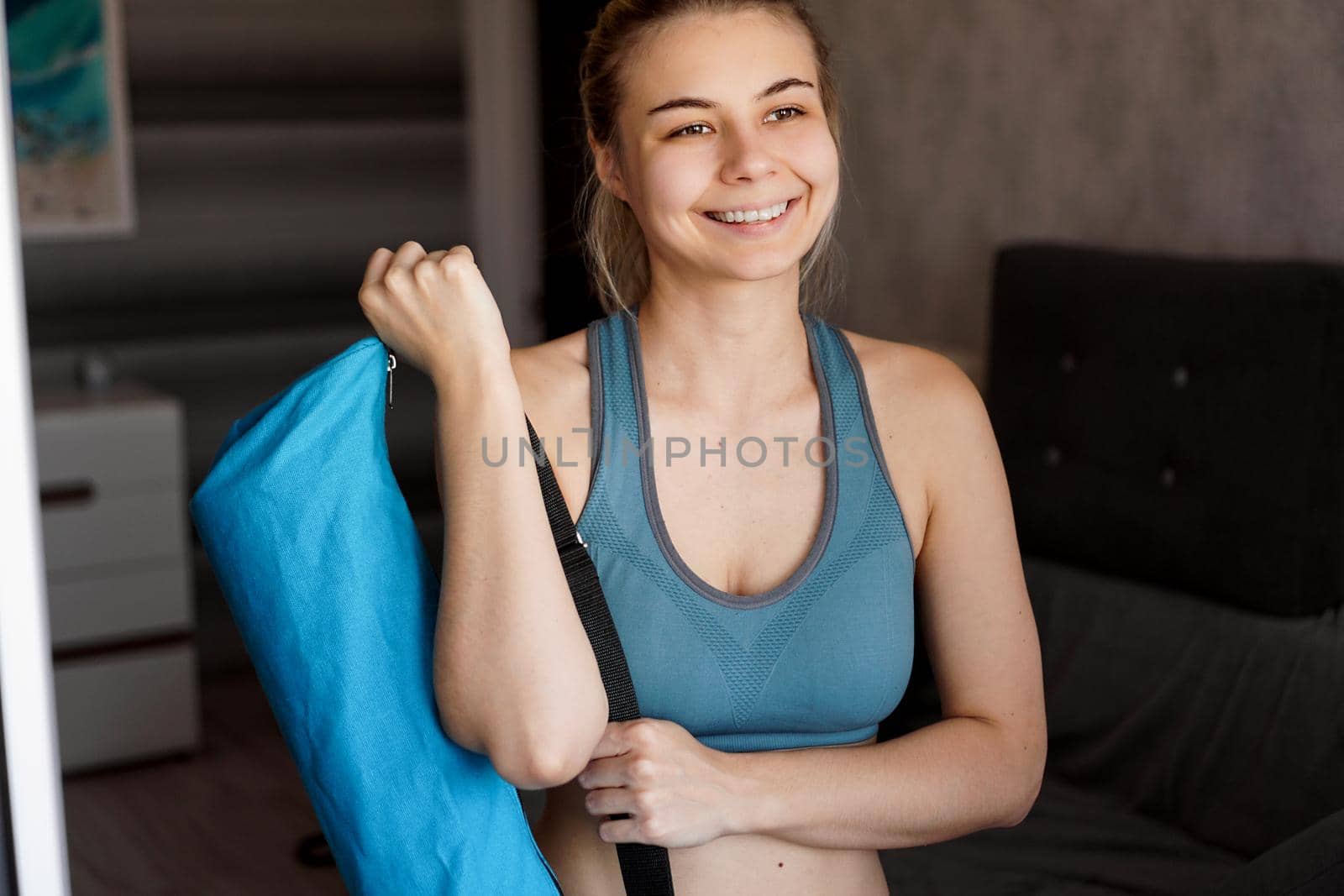 Portrait of an athletic happy young woman. She is going to workout, yoga mat case in hand