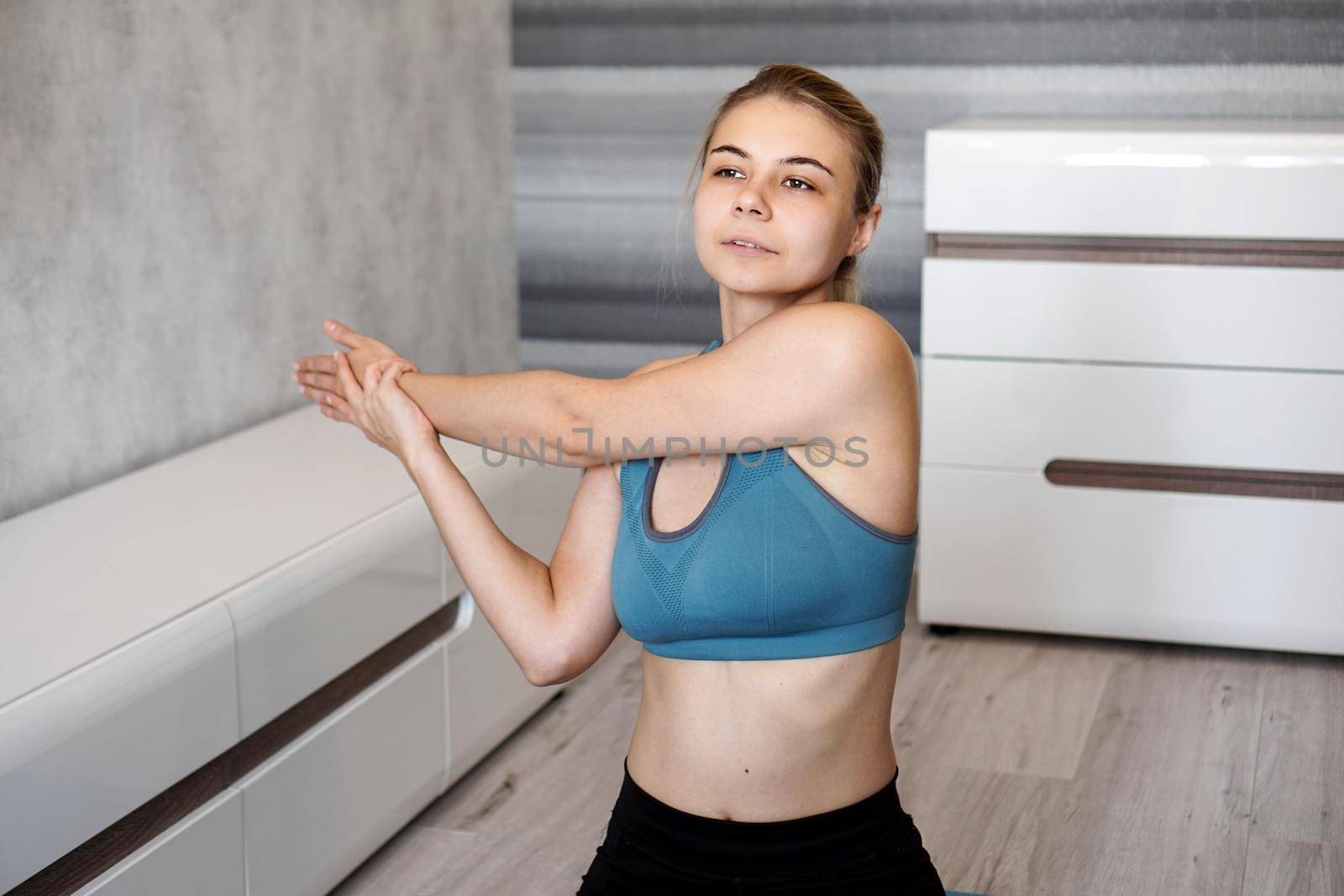 Fitness, home and diet concept. Smiling girl streching on floor at home. Stretching the arms and shoulders