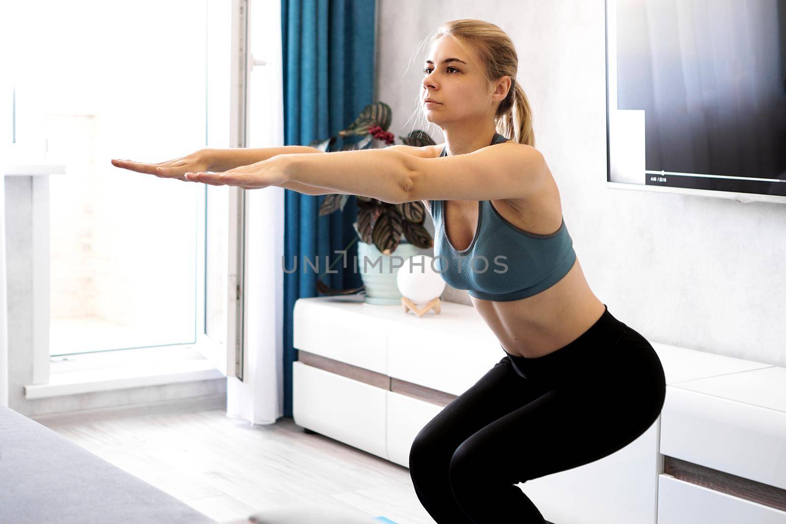 Fitness, sport, training and lifestyle concept - woman exercising and doing squats at home
