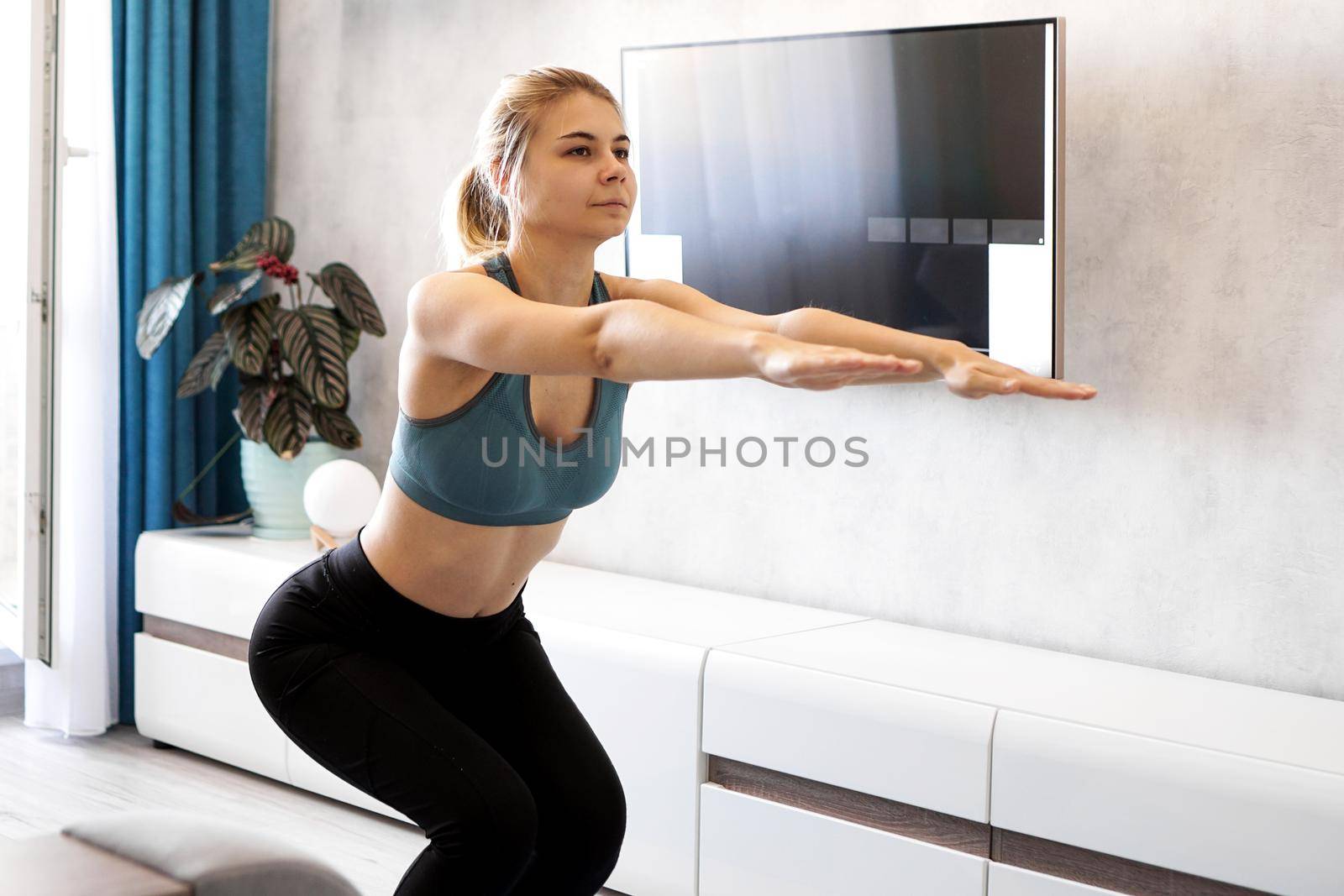 Training and lifestyle concept - woman exercising and doing squats at home by natali_brill