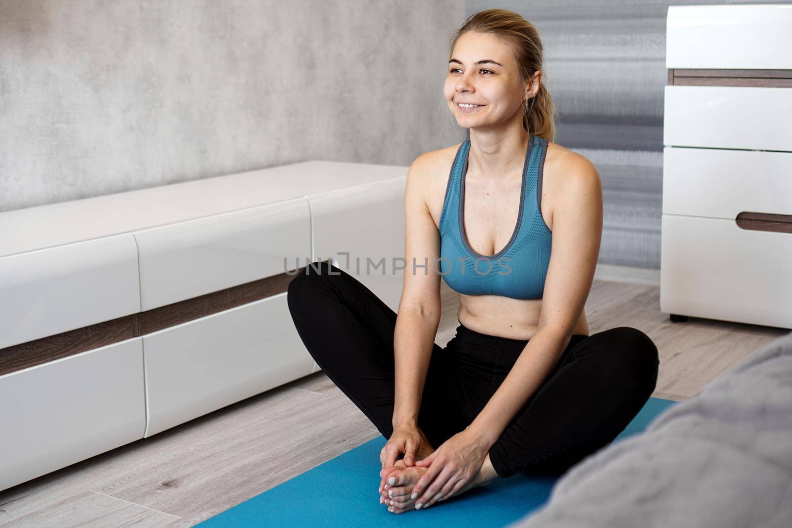 Happy fitness woman yoga relax meditation in butterfly pose at home. Young slim girl makes exercise