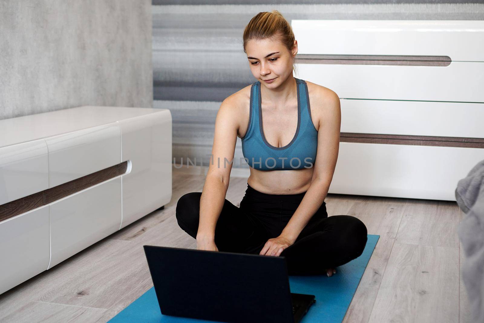 Girl training at home and watching videos on laptop before starting, training in living room