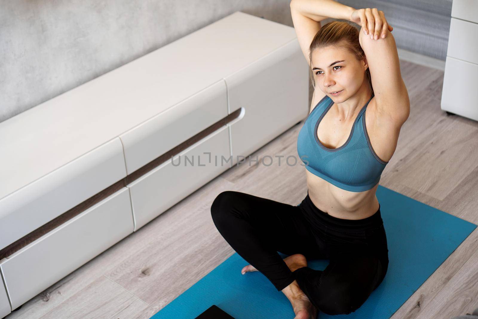 Young athletic woman doing stretching before home workout. Fitness trainer at home