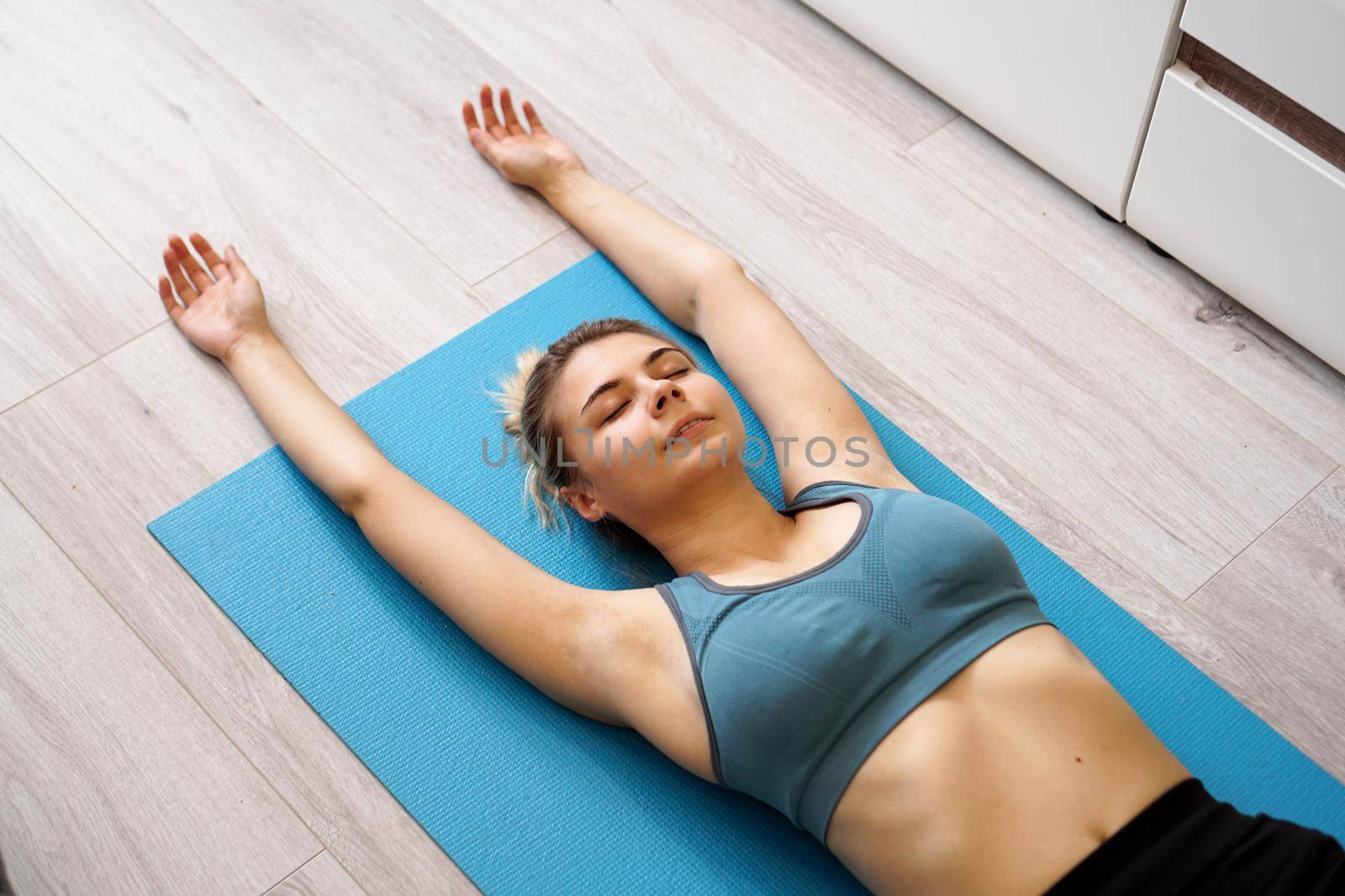 Top view of beautiful young woman lying on yoga mat after workout by natali_brill