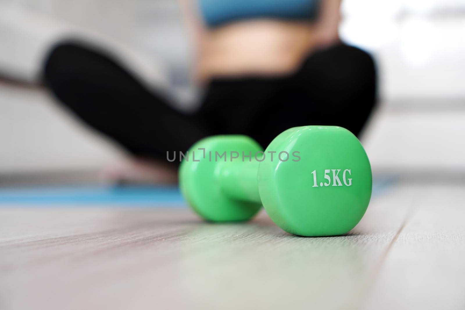 Close up of dumbbell and woman stretching in blurred background. Healthy lifestyle concept