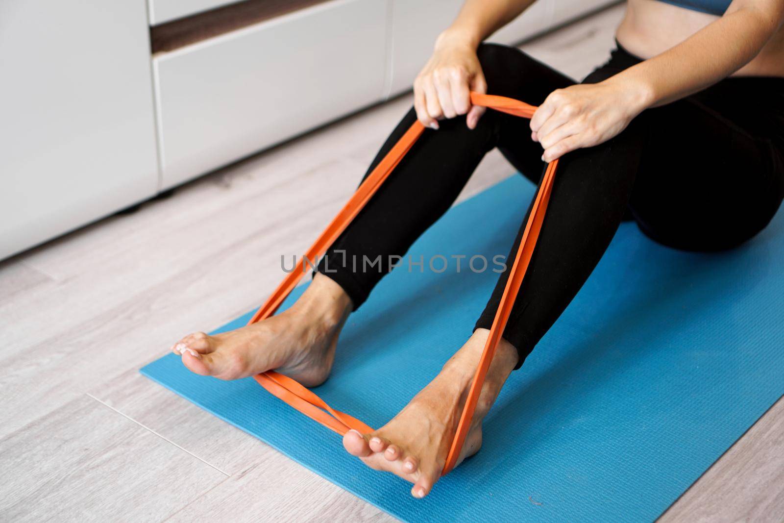 Young woman with elastic band. She trains her legs at home. Healthcare and lifestyle concept