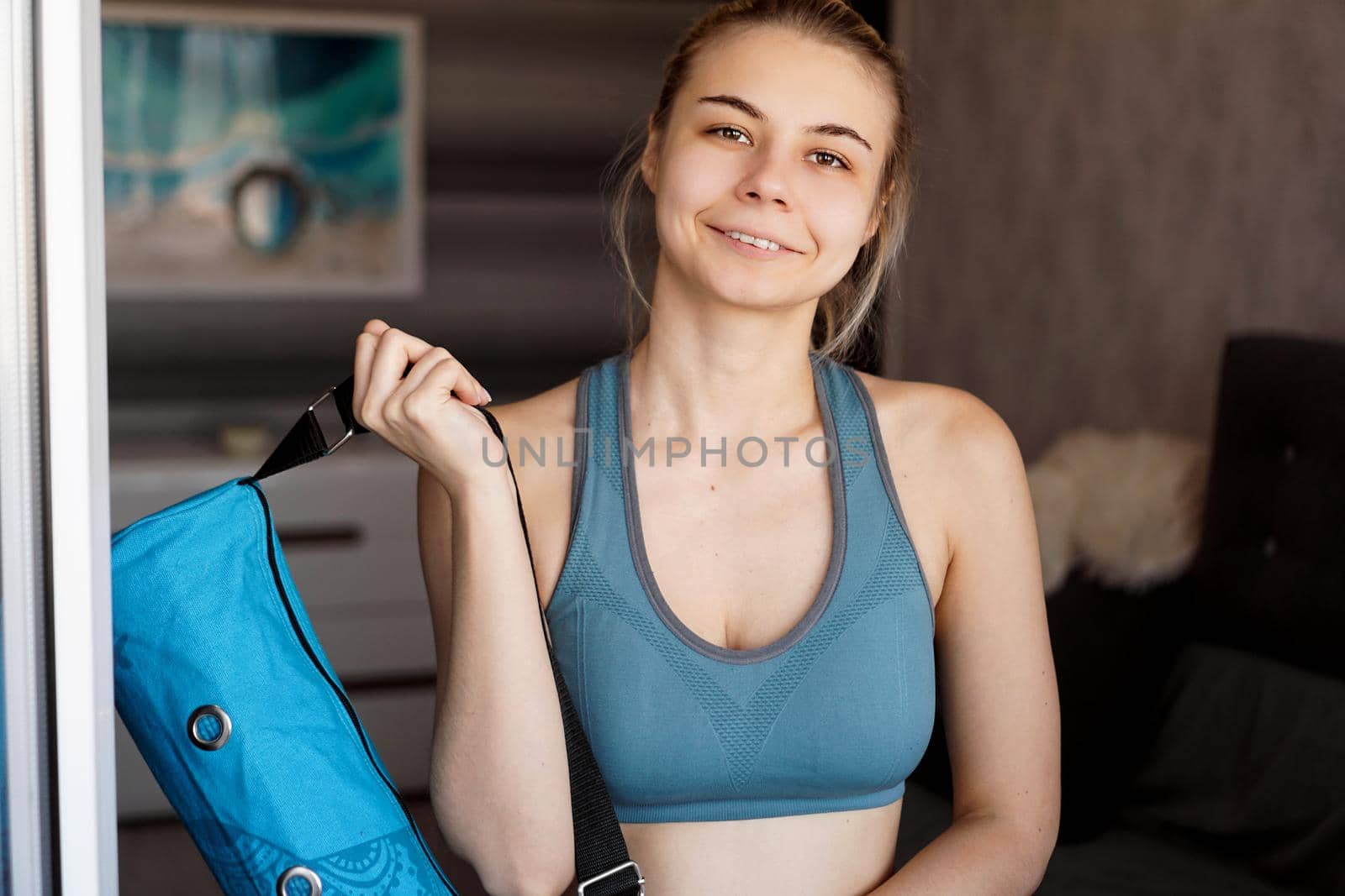 Portrait of an athletic young woman. She is going to workout, yoga mat case in hand