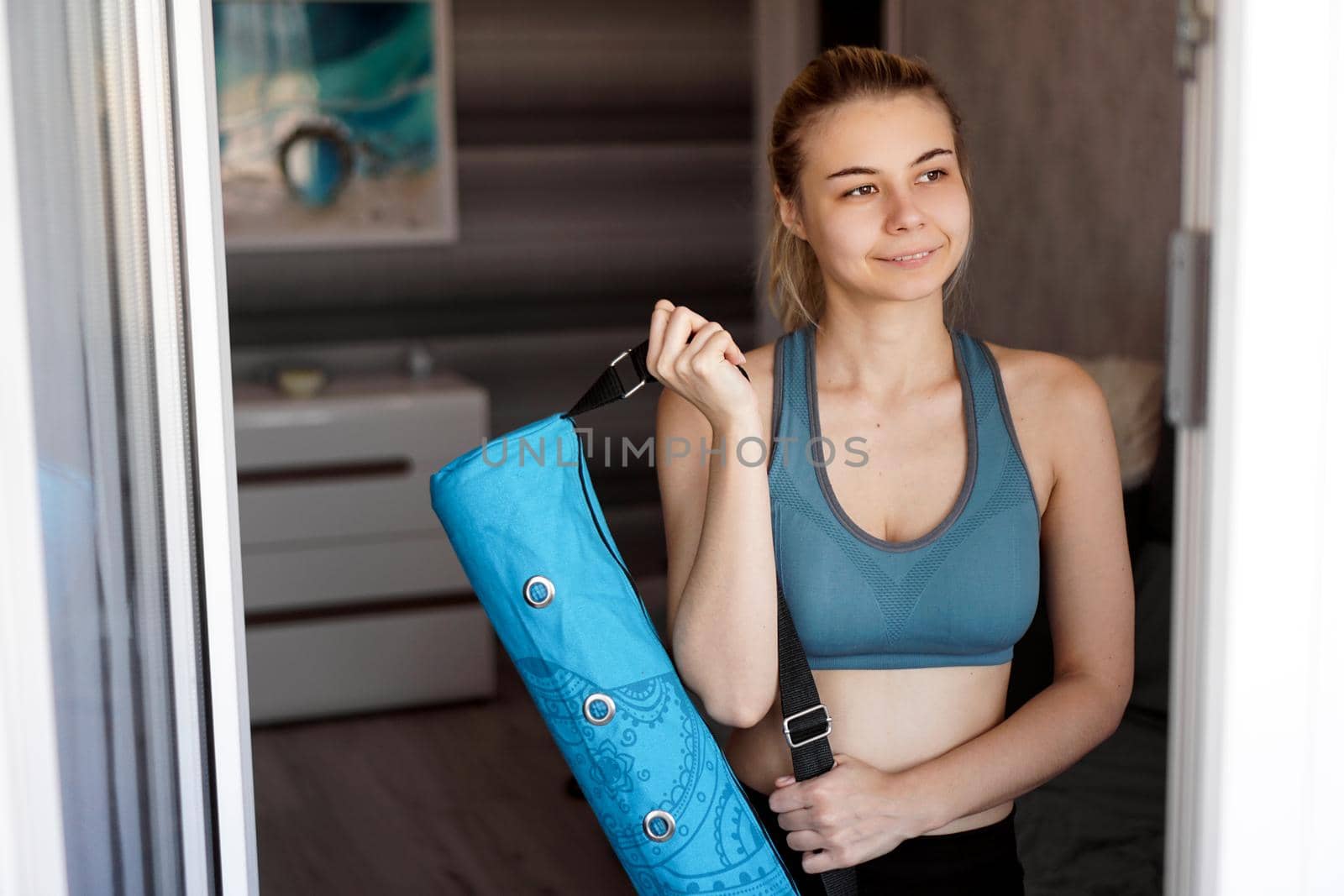 Portrait of an athletic young woman. She is going to workout, yoga mat case in hand