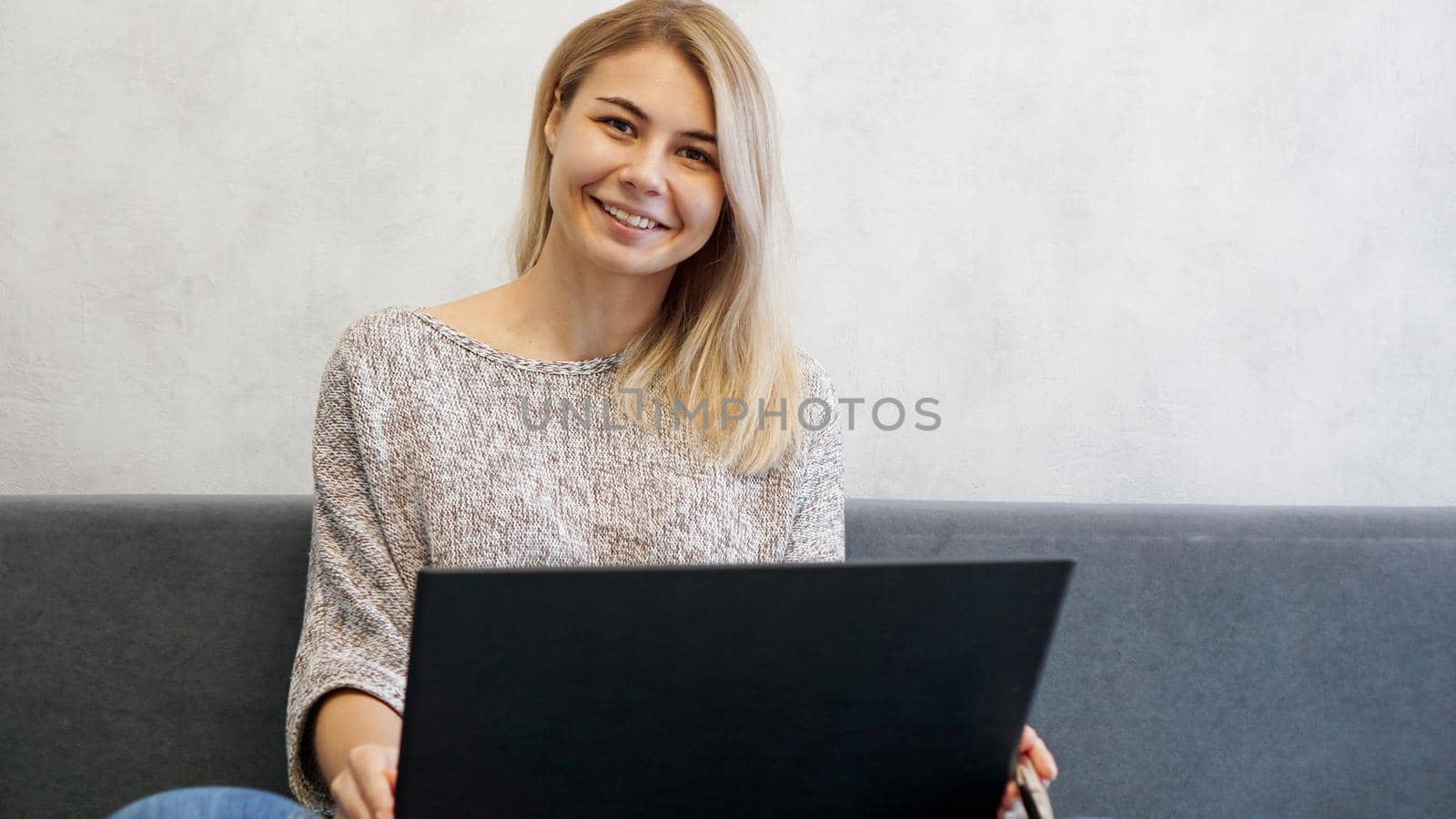 Casual young woman using laptop in living room at home. Working from home by natali_brill
