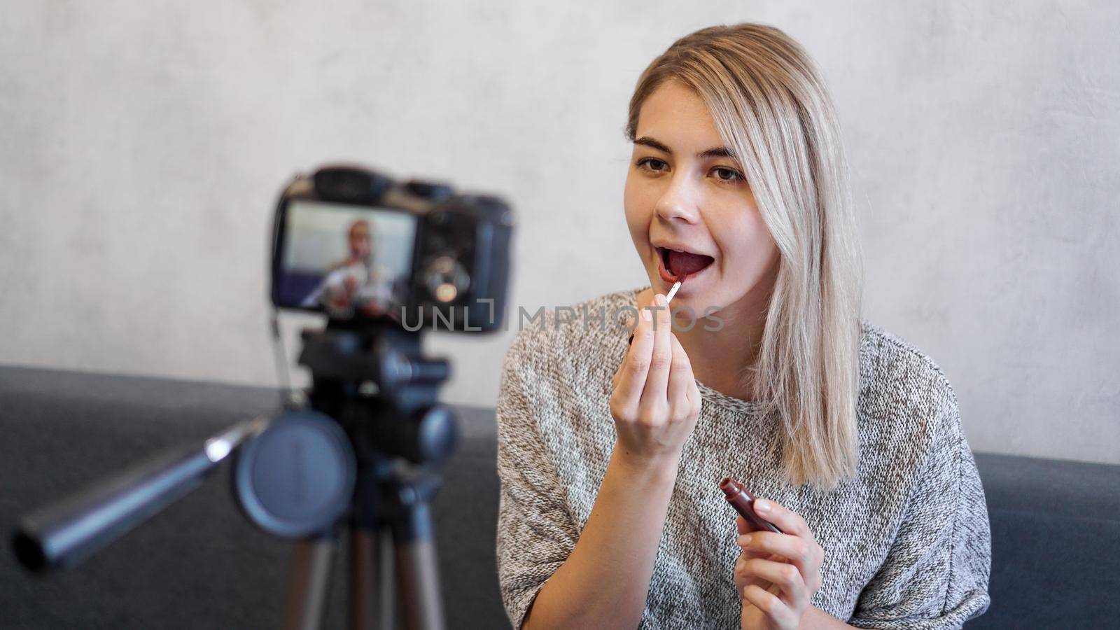 A beauty blogger or video blogger tells and shows subscribers how to do makeup. Young woman paints lips