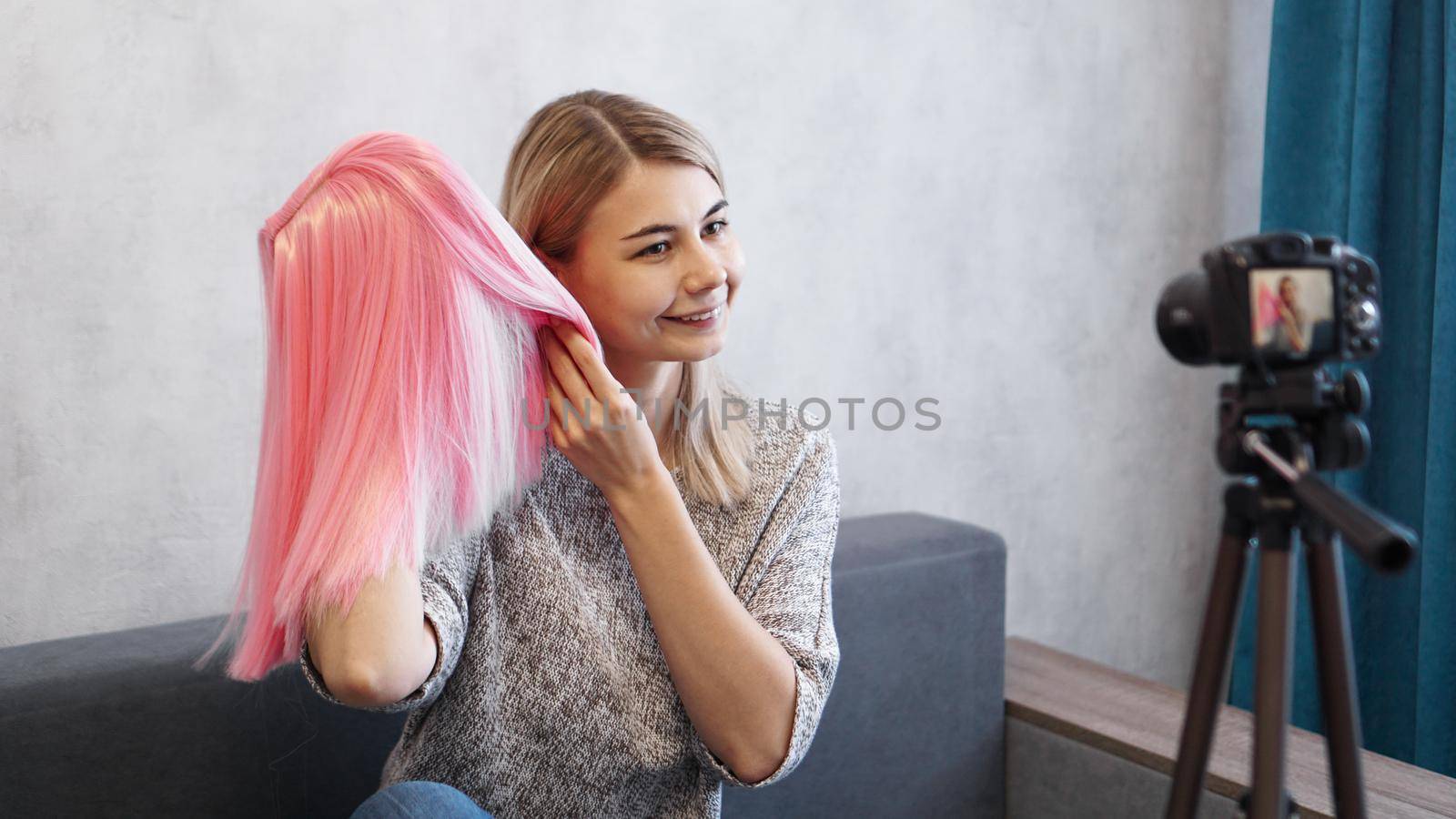 Woman blogger records video. She talks about haircuts and shows a pink wig. Stylist and fashion consultant recording the lecture