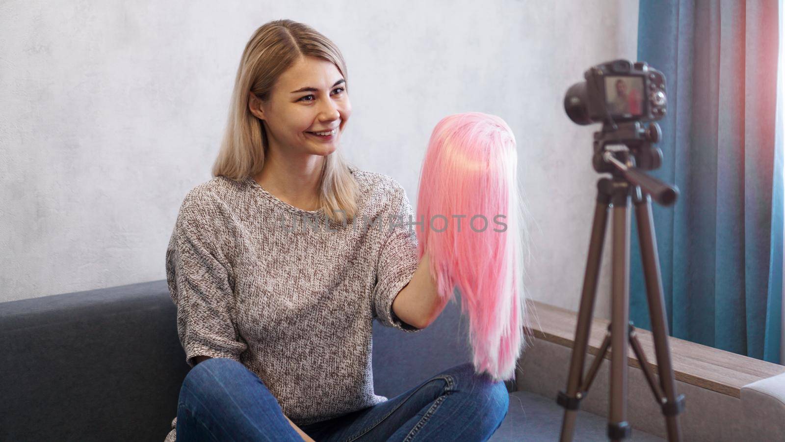 Woman blogger records video. She talks about haircuts and shows a pink wig. Stylist and fashion consultant recording the lecture