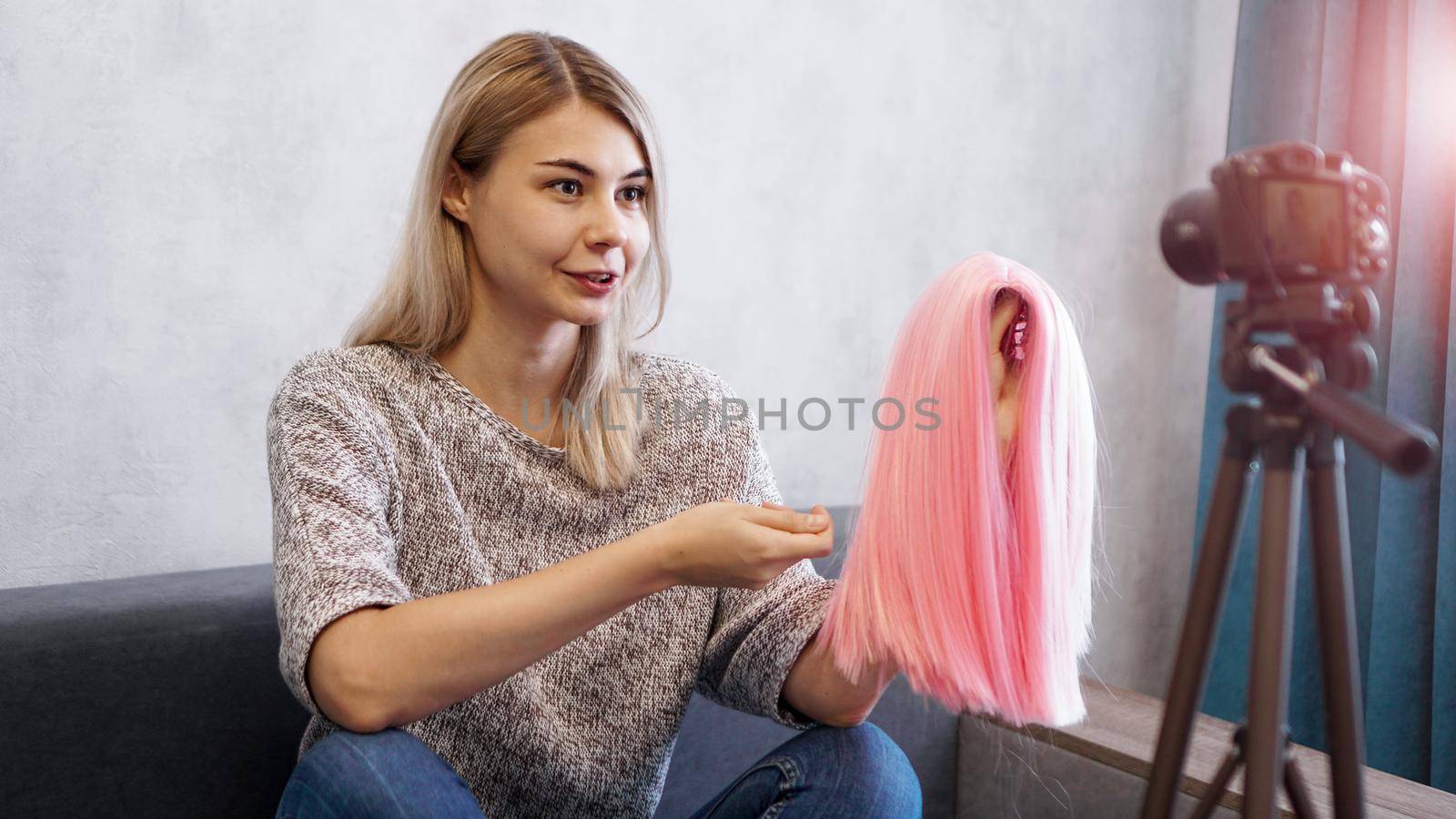 Woman blogger records video. She talks about haircuts and shows a pink wig. Stylist and fashion consultant recording the lecture