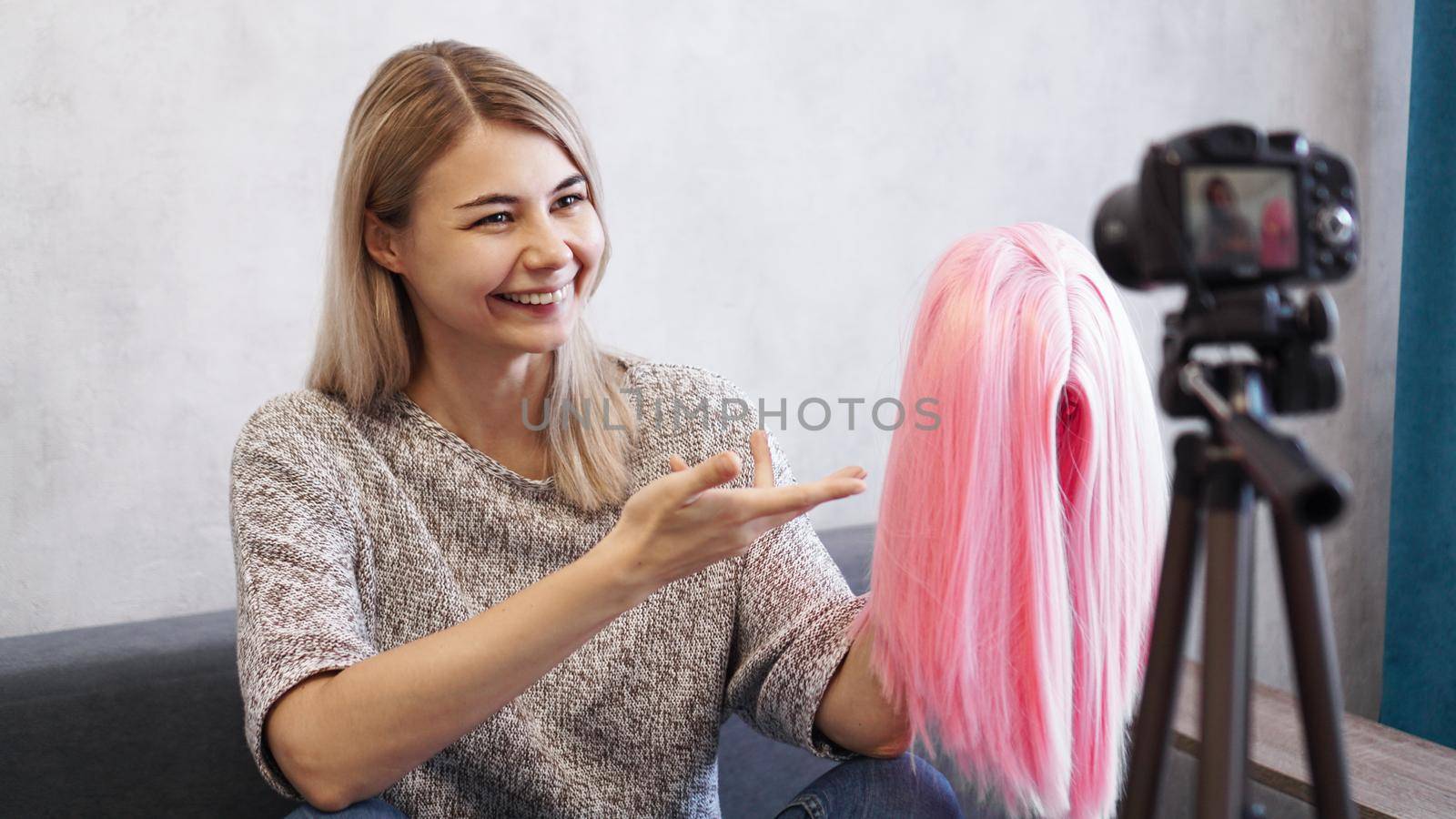 Woman blogger records video. She talks about haircuts and shows a pink wig. Stylist and fashion consultant recording the lecture