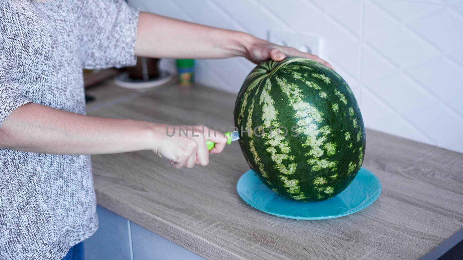 Closeup of woman hand cutting watermelon in the kitchen by natali_brill