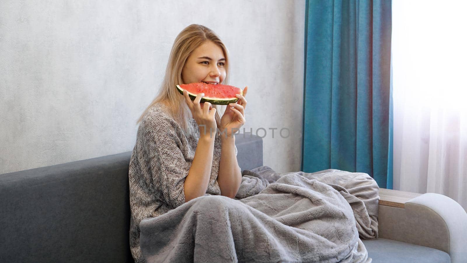 Young attractive woman eating watermelon. Woman at home in a cozy interior