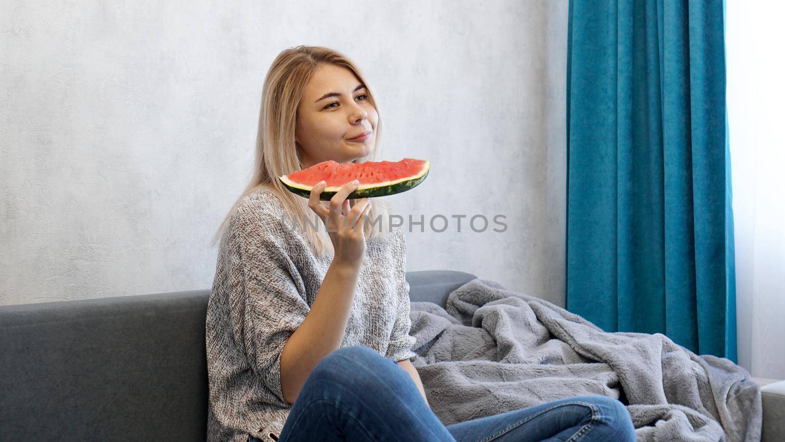 Young attractive woman eating watermelon. Woman at home in a cozy interior