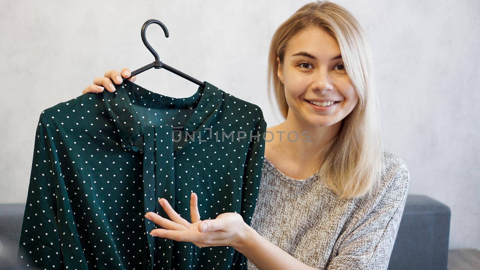 Beautiful woman shows a dress on a hanger. She talks about fashion and records a video blog