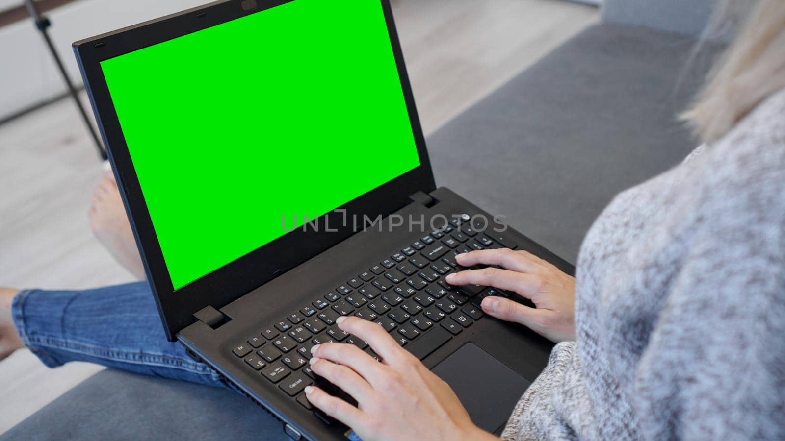 Woman using laptop with green screen. Woman typing on a laptop keyboard. Business, communication, freelance and internet concept