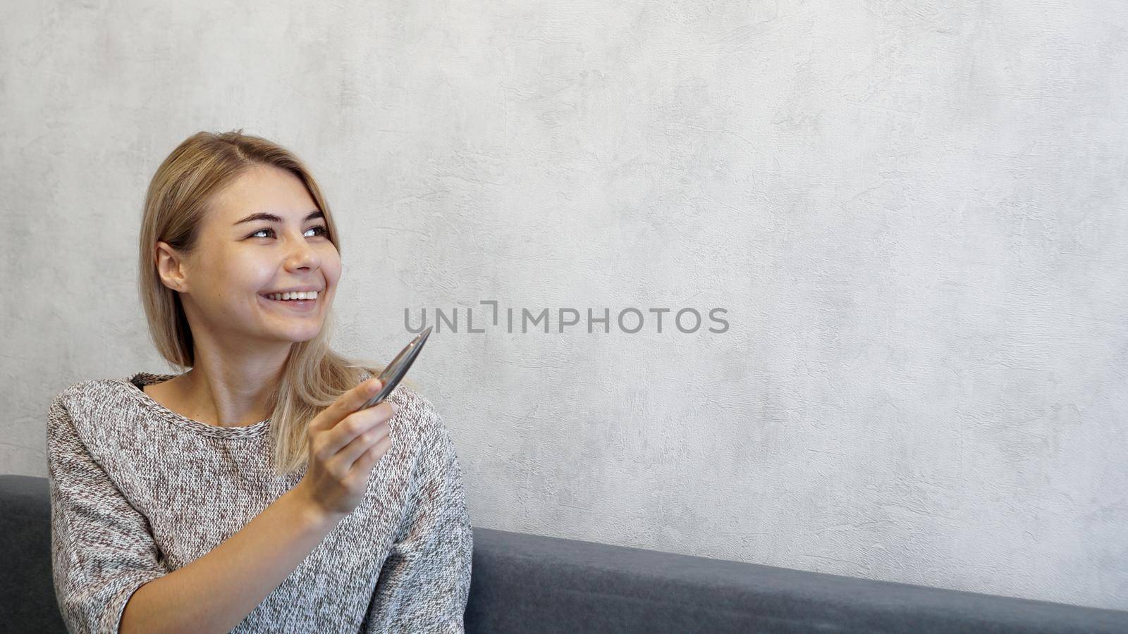 The woman shows with a pen on a gray wall. Place for information - graphics, inscriptions, banners